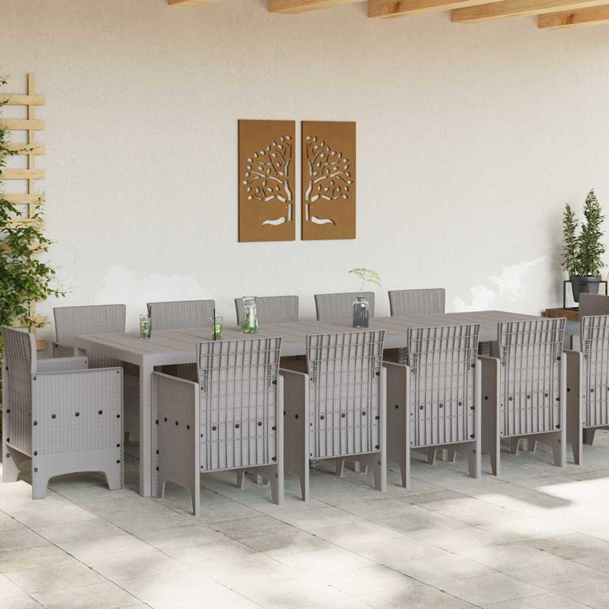 Eine Essgruppe im Freien mit einem langen Tisch und Stühlen. An der Wand befinden sich dekorative Baumfelder. Der Boden ist gefliest.