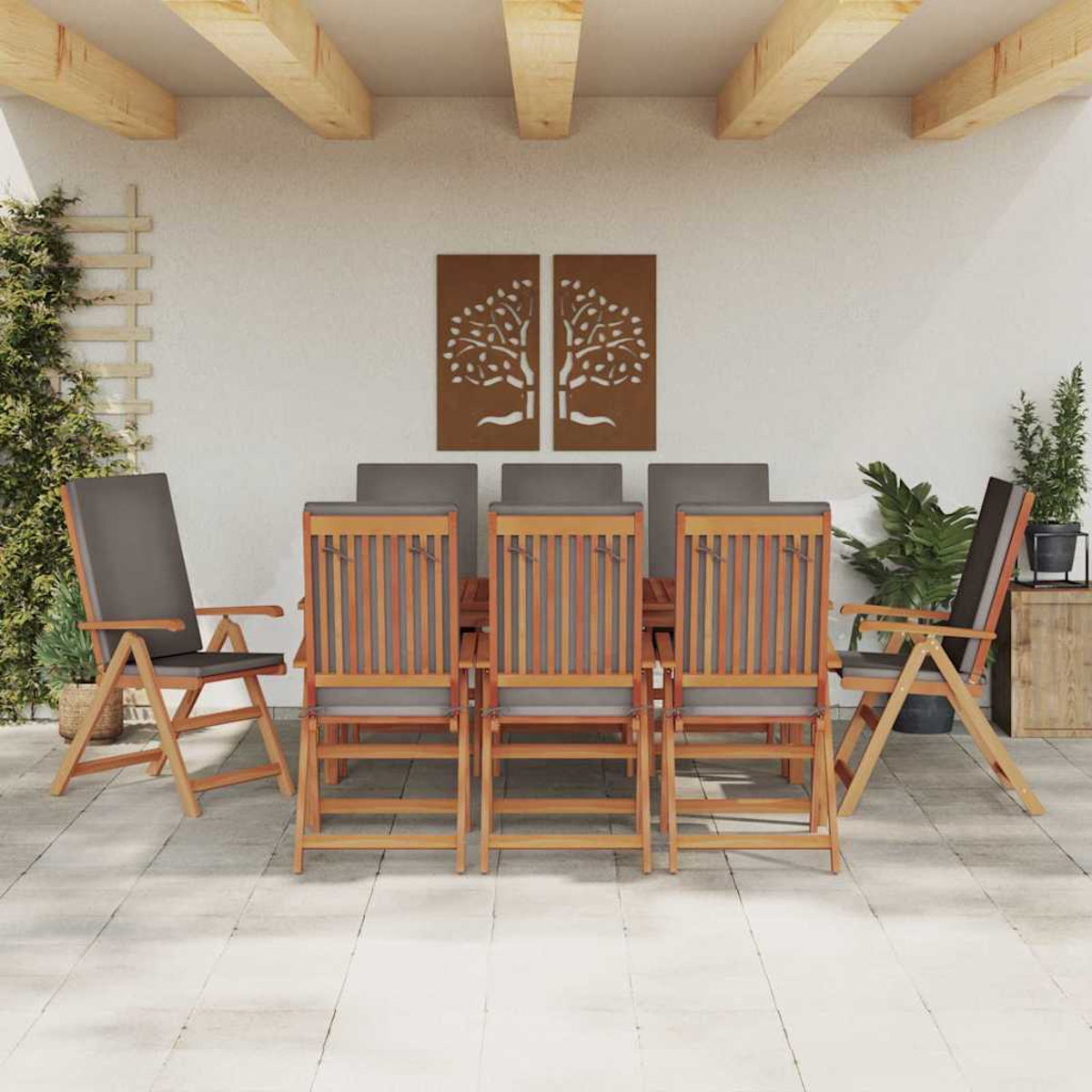Essgruppe im Freien: Holzstühle mit grauen Kissen um einen Tisch. Hintergrund zeigt Wandkunst und Pflanzen.
