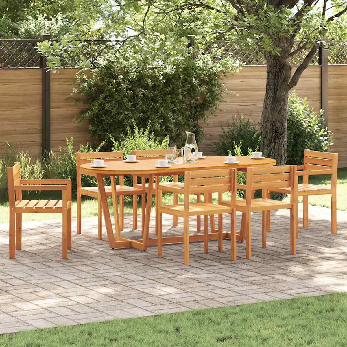 Juego de patio de madera con mesa redonda y seis sillas. Tazas, vasos y una jarra sobre la mesa. Hierba verde y árboles al fondo.