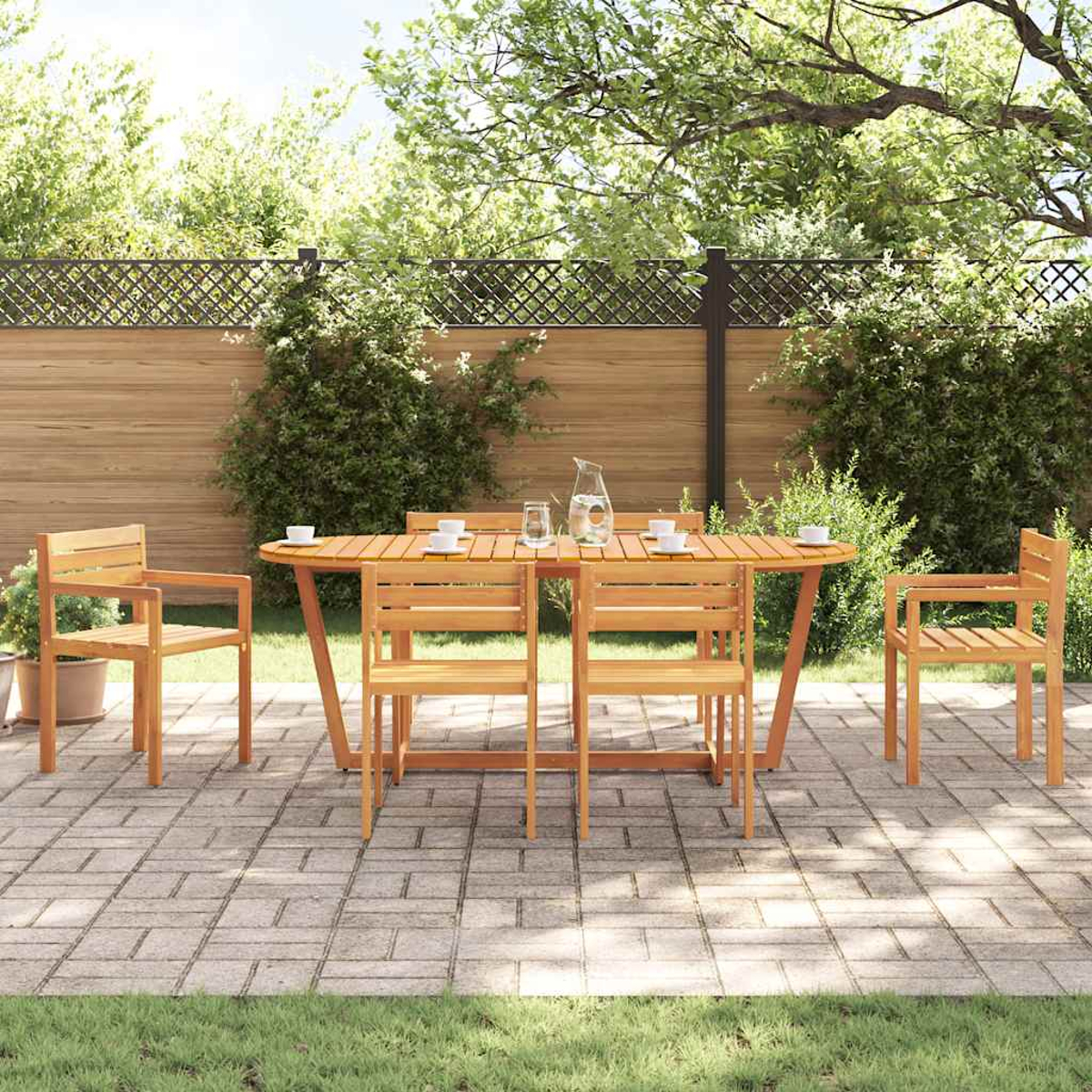 Juego de patio de madera con mesa y sillas. Mesa con platos y jarra de agua. Árboles y valla de madera al fondo.