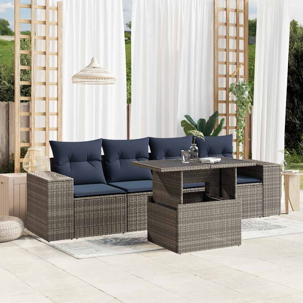 Garten-Sitzgruppe mit blauen Kissen und Tisch vor weißen Vorhängen und Holzgittern.