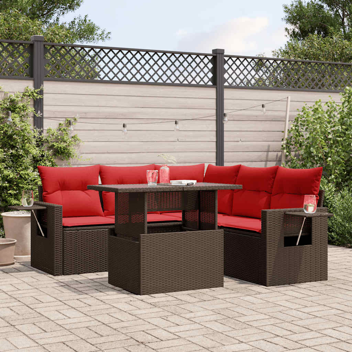 Outdoor-Terrassenset mit braunen Korbmöbeln und roten Kissen. Ein Tisch steht im Zentrum, im Hintergrund ein Zaun.