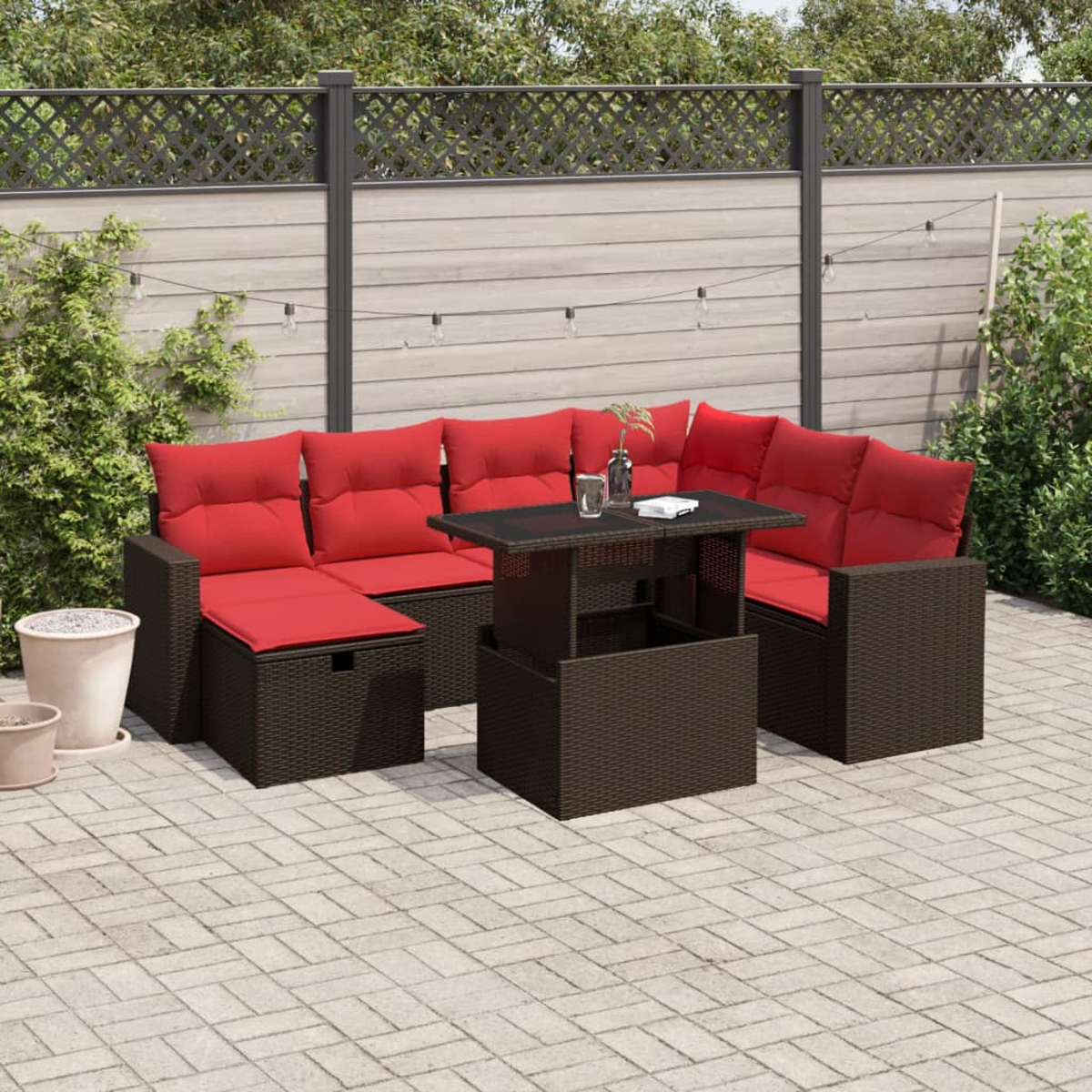 Garten-Set mit roten Kissen auf braunem Korbgeflecht. Enthält einen Tisch, ein Sofa und einen Stuhl. Auf einer Backstein-Terrasse mit Zaun.