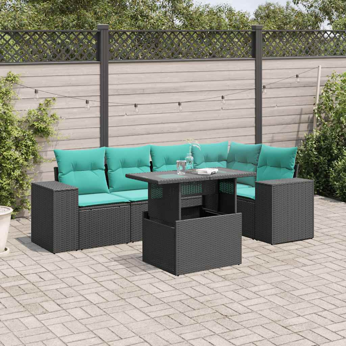 Terrassenset mit tealfarbenen Kissen und einem Tisch mit Hubfunktion auf einer gepflasterten Terrasse. Im Hintergrund ein Zaun und Grün.