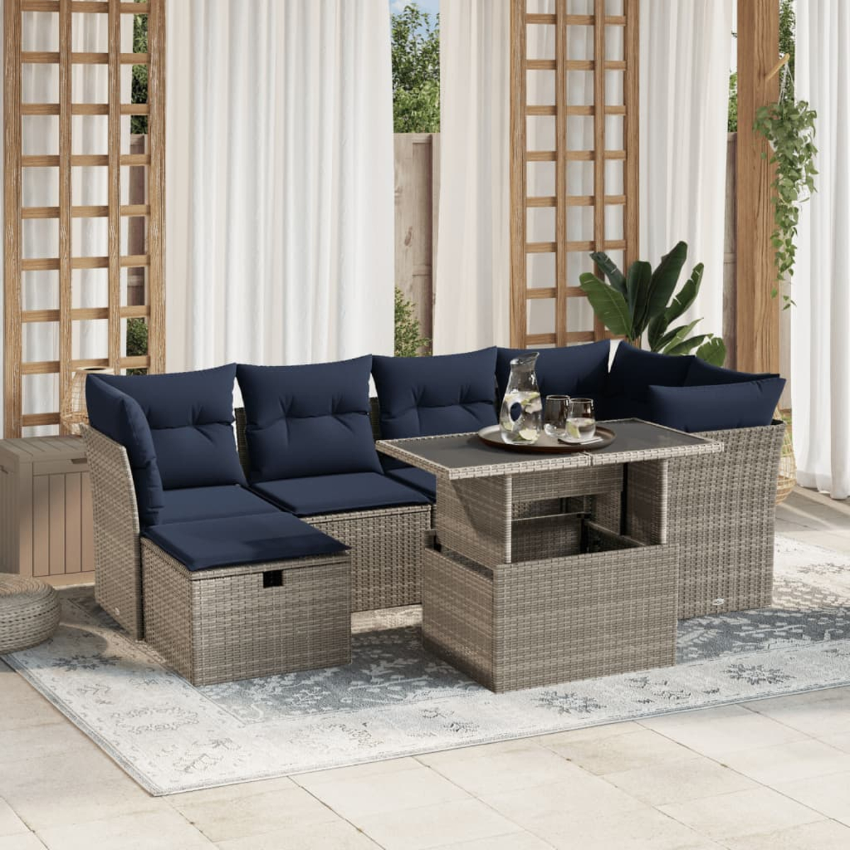 Outdoor-Ecksofa mit marineblauen Kissen und einem Tisch mit Hubfunktion, auf einem gemusterten Teppich, mit weißen Vorhängen und Holzakzenten.