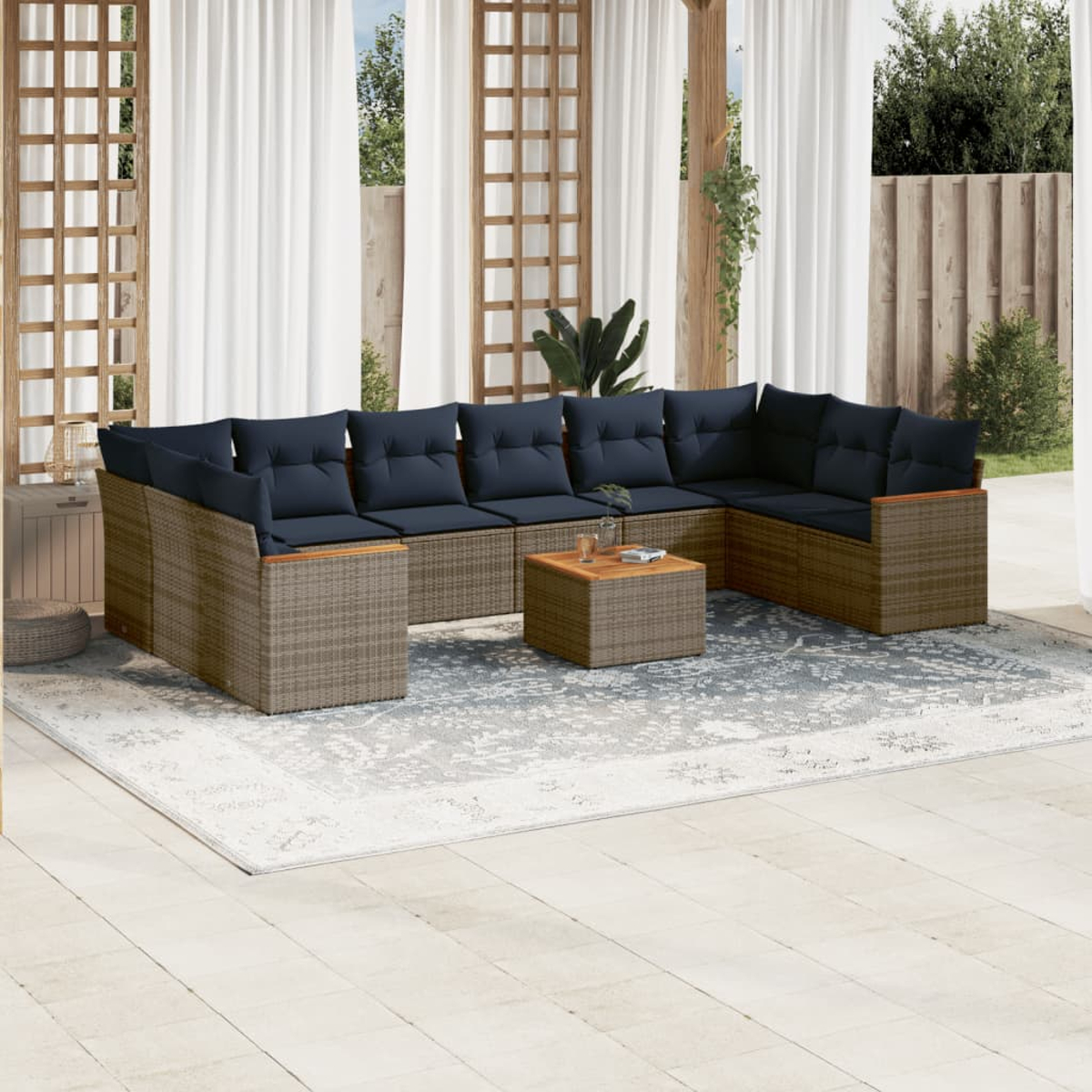 Outdoor-Ecksofa mit marineblauen Kissen, einem Couchtisch und einem gemusterten Teppich auf einer Terrasse. Hintergrund mit Vorhängen und Grün.