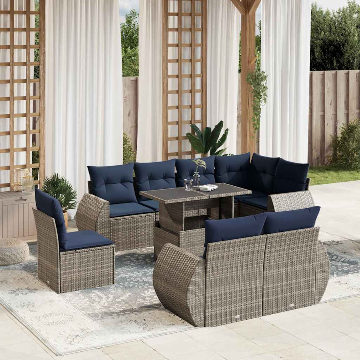 Gartenmöbel-Set mit blauen Kissen, Tisch, Teppich und Vorhängen. Szene in einem Hinterhof mit Grün.