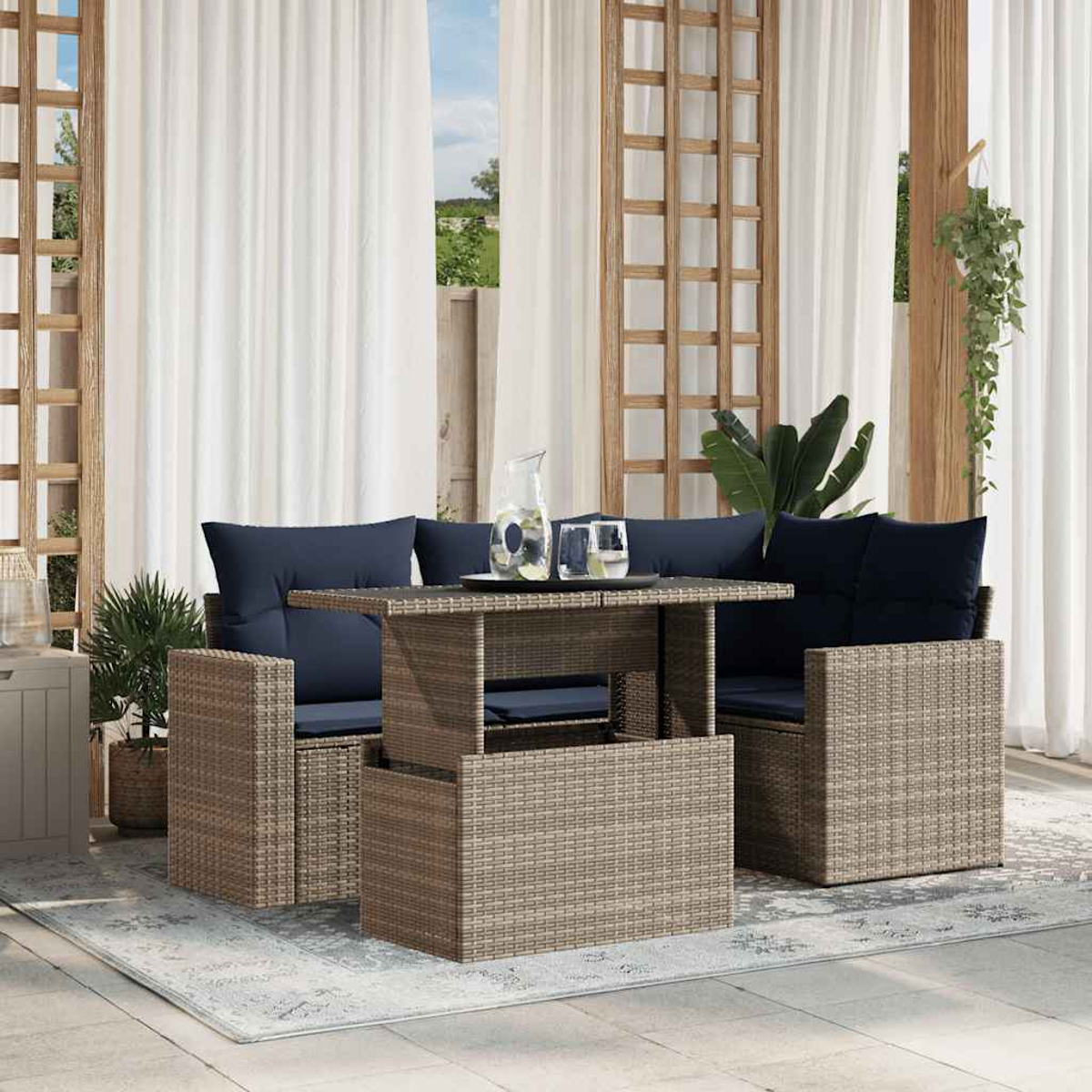 Terrassenmöbel-Set mit gewebten Stühlen, marineblauen Kissen und einem Tisch mit Getränken. Vorhänge und Pflanzen vervollständigen die Szene.