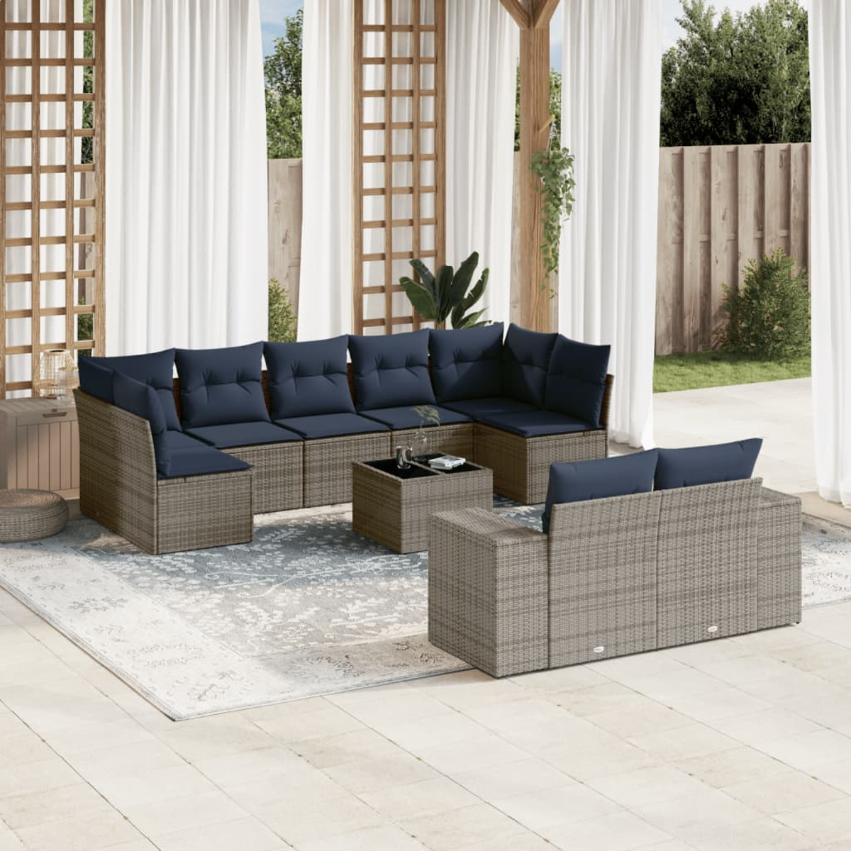 Garten-Sitzgruppe mit blauen Kissen. Umfasst ein Ecksofa, eine Sitzbank und einen Couchtisch auf einem Teppich. Hintergrund mit Vorhängen und Pflanzen.