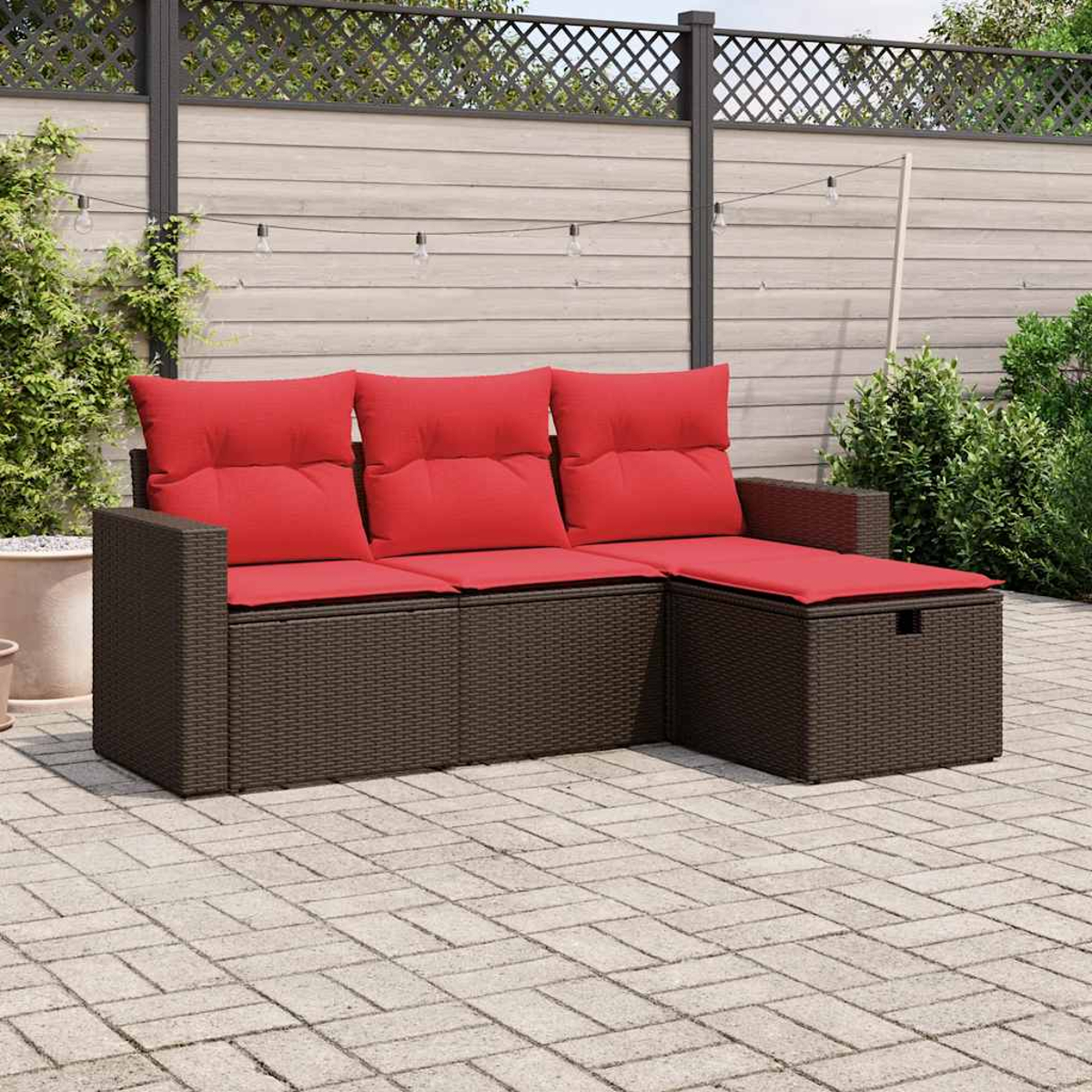 Braunes Outdoor-Sofa aus Korbgeflecht mit roten Kissen auf einer Ziegelterrasse. Hintergrund: Holzzaun, Lichterkette und Grün.