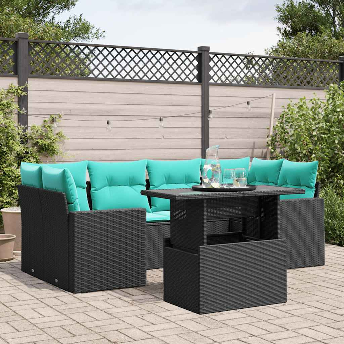 Garten-Sitzgruppe mit schwarzen Korbmöbeln und türkisfarbenen Kissen. Vorne steht ein Tisch mit einem Tablett mit Getränken.