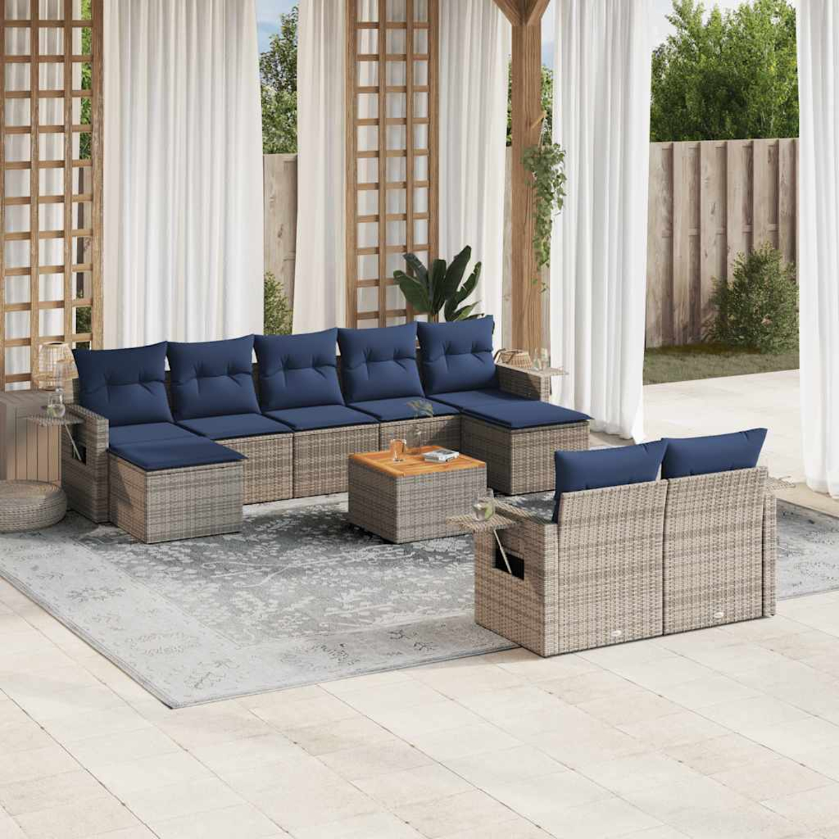 Outdoor-Ecksofa mit blauen Kissen, einem Couchtisch und einem Teppich. Weiße Vorhänge und Holzstruktur. Grünes Laub im Hintergrund.