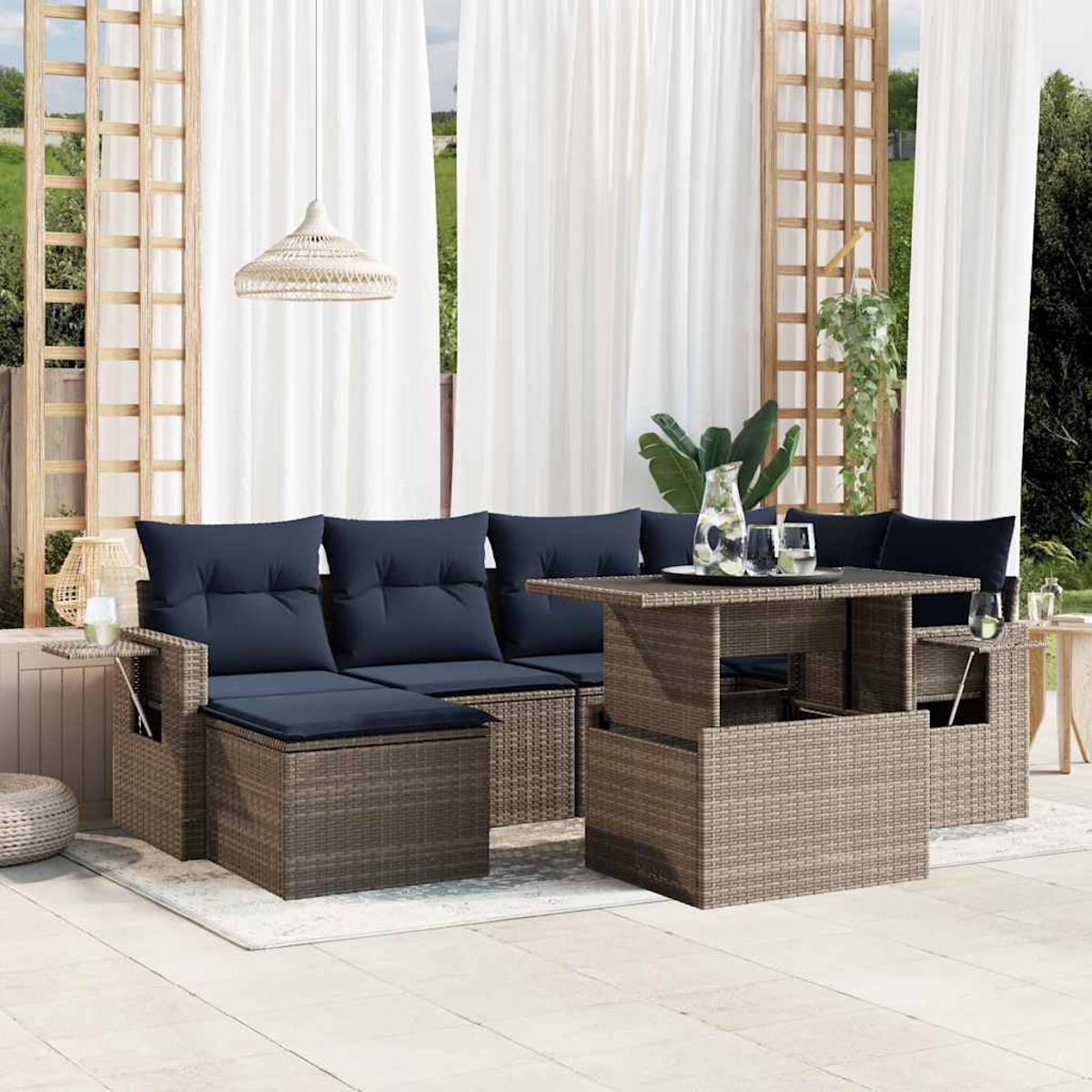 Geflochtener Outdoor-Schnitt mit marineblauen Kissen, Couchtisch, weißen Vorhängen und einer Hängelampe. Eine entspannende Terrasse.