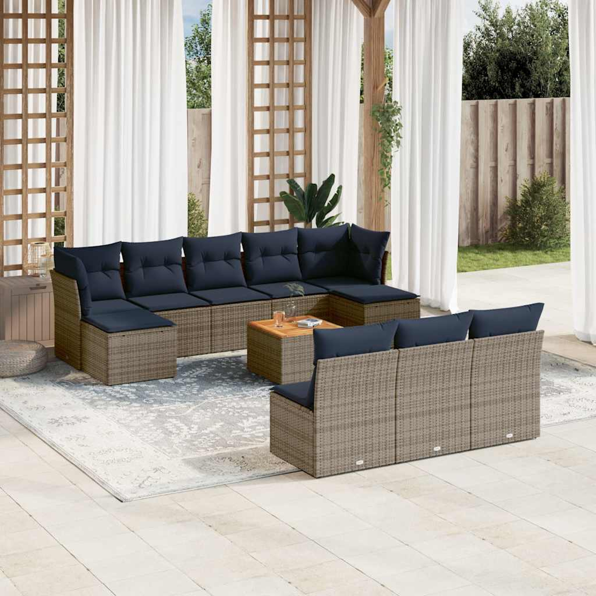 Outdoor-Terrassenset mit Korbsitzgruppen, marineblauen Kissen und einem Holztisch. Weiße Vorhänge und ein Holzgitter im Hintergrund.