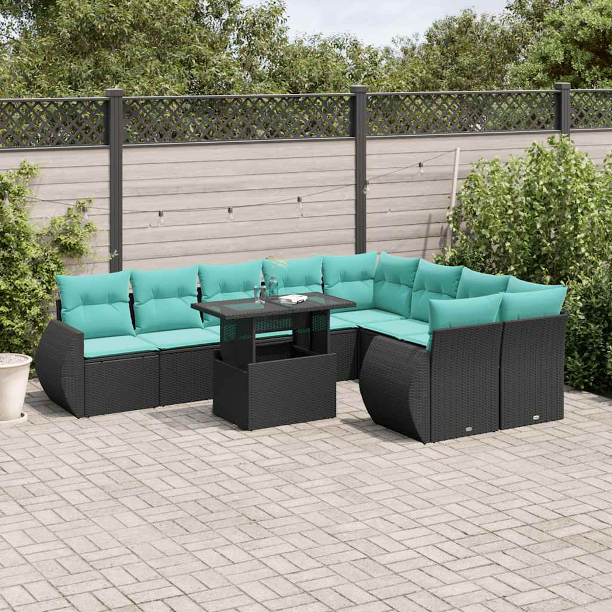Outdoor-Ecksofa mit türkisfarbenen Kissen und einem schwarzen Tisch auf einer Backstein-Terrasse. Im Hintergrund sind Zaun und Grün.