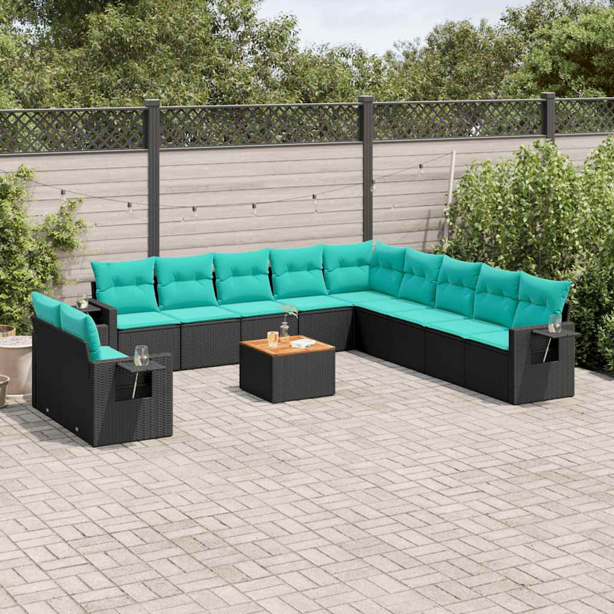 Ein Outdoor-Terrassenset mit schwarzen Korbmöbeln, türkisfarbenen Kissen und einem Holztisch auf einer Backsteinterrasse.