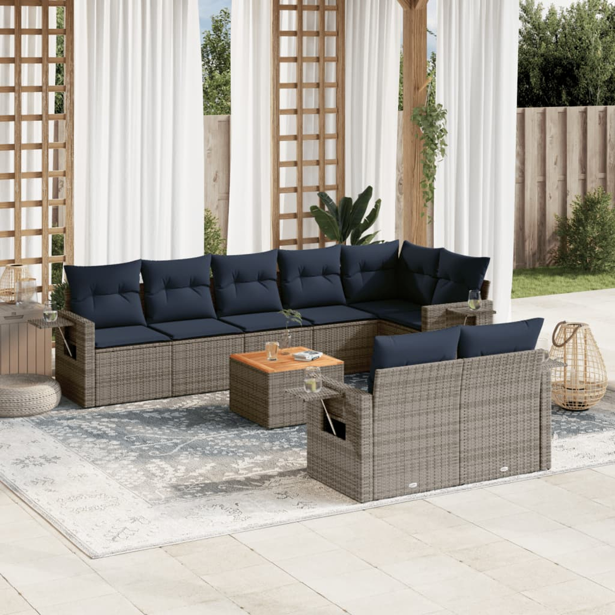 Terrassenset im Freien mit blauen Kissen, Holztisch und Teppich. Im Hintergrund Vorhänge, Holzstruktur und Pflanzen.