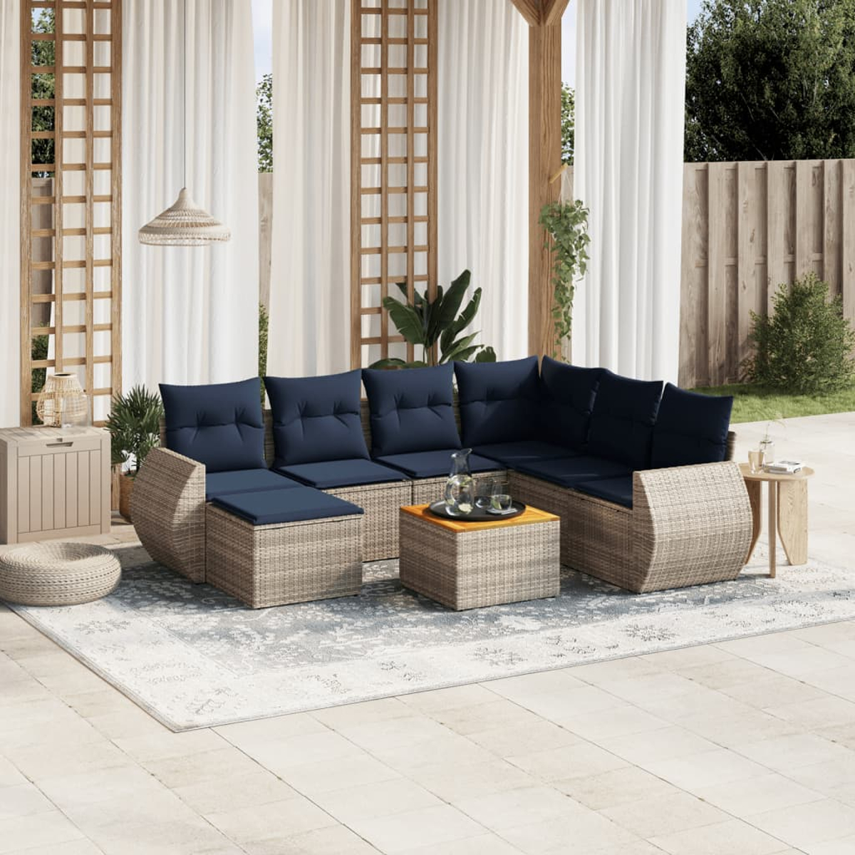Outdoor-Ecksofa mit marineblauen Kissen. Beige gewebte Möbel, Teppich, Beistelltisch und weiße Vorhänge. Terrasse mit Pflanzen.