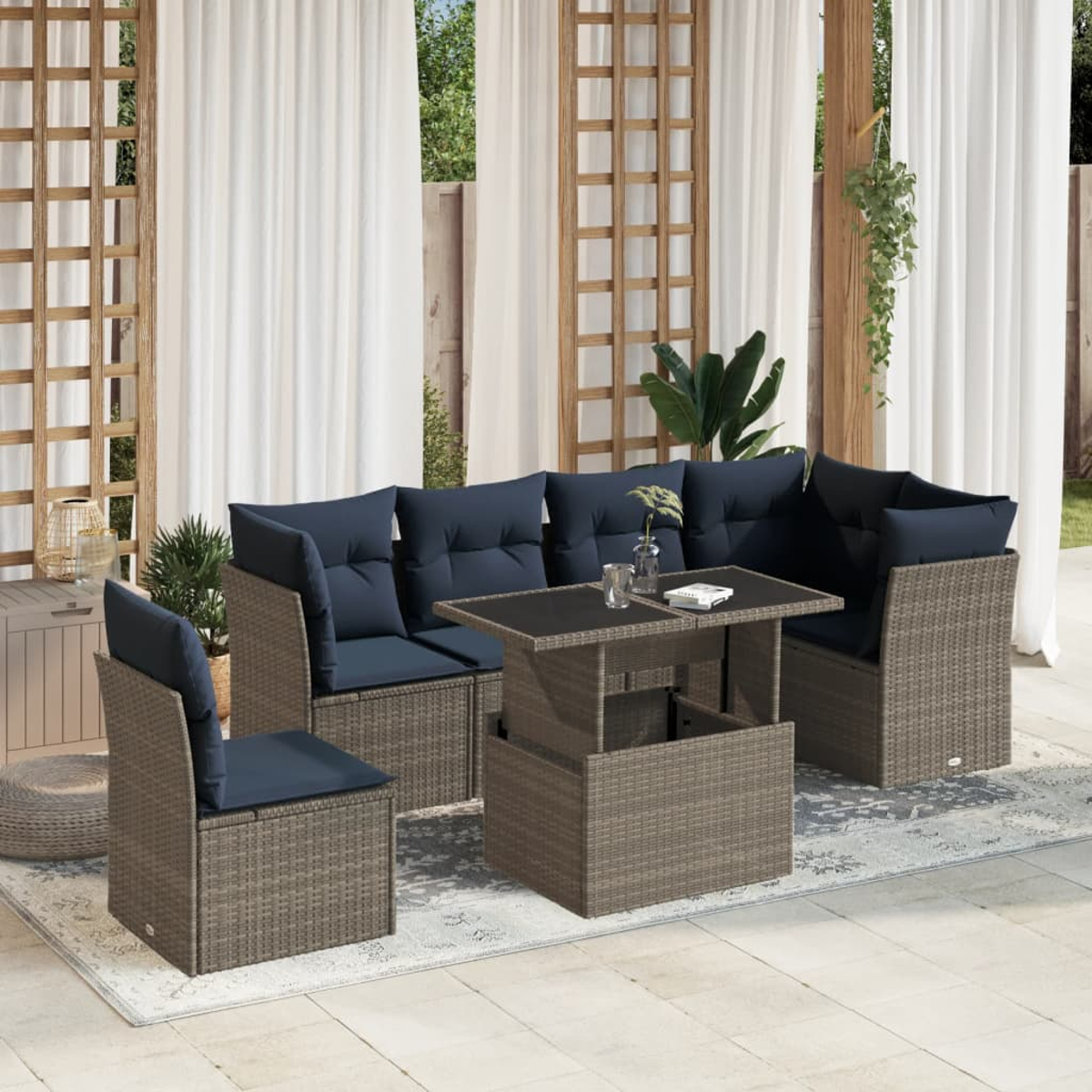 Gartenmöbel-Set: Korbsessel mit blauen Kissen, Tisch und Stuhl. Im Hintergrund weiße Vorhänge, Holzgitter und Pflanzen.