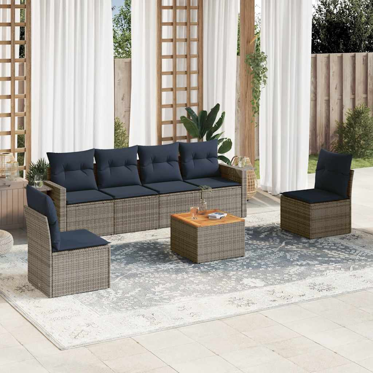 Gartenmöbel-Set. Mit Sofa, zwei Stühlen und Couchtisch auf gemustertem Teppich, mit weißen Vorhängen im Hintergrund.