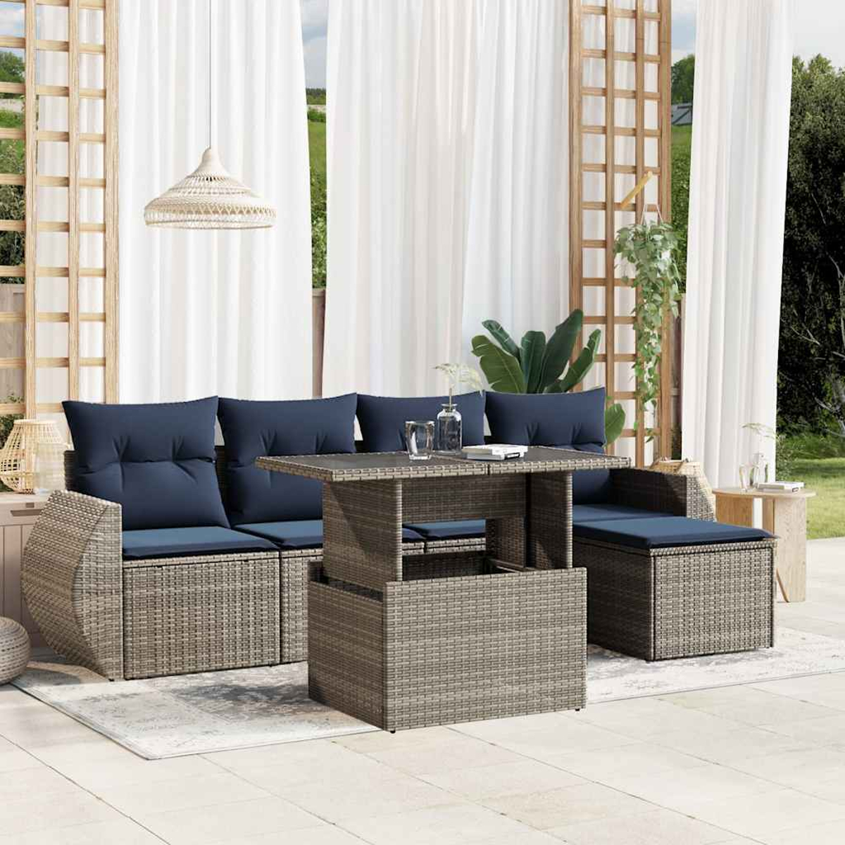 Outdoor-Möbel-Set mit Sofa, Tisch und Ottomane. Blaue Kissen auf grauen, gewebten Rahmen. Weiße Vorhänge und Hängelampe im Hintergrund.