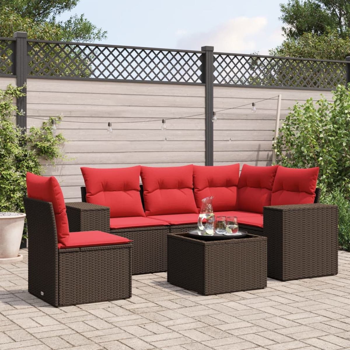 Terrassengarnitur mit roten Kissen und braunen Korbmöbeln. Beinhaltet ein Sofa, Stühle und einen Couchtisch. Auf einer Terrasse.