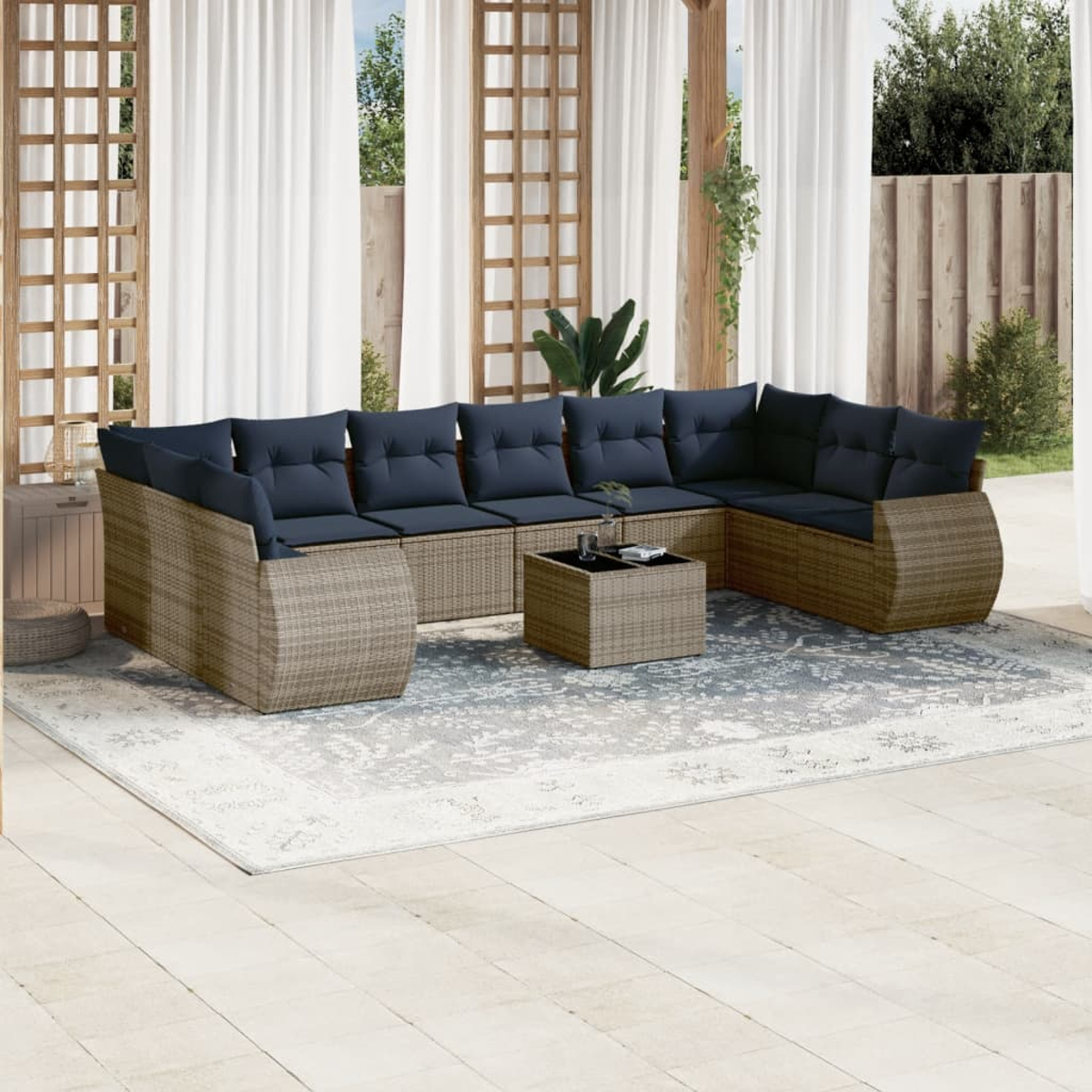 Außenbereich mit großem Korbmöbel-Sofa mit blauen Kissen und einem Couchtisch. Die Szene spielt sich auf einem Teppich ab.
