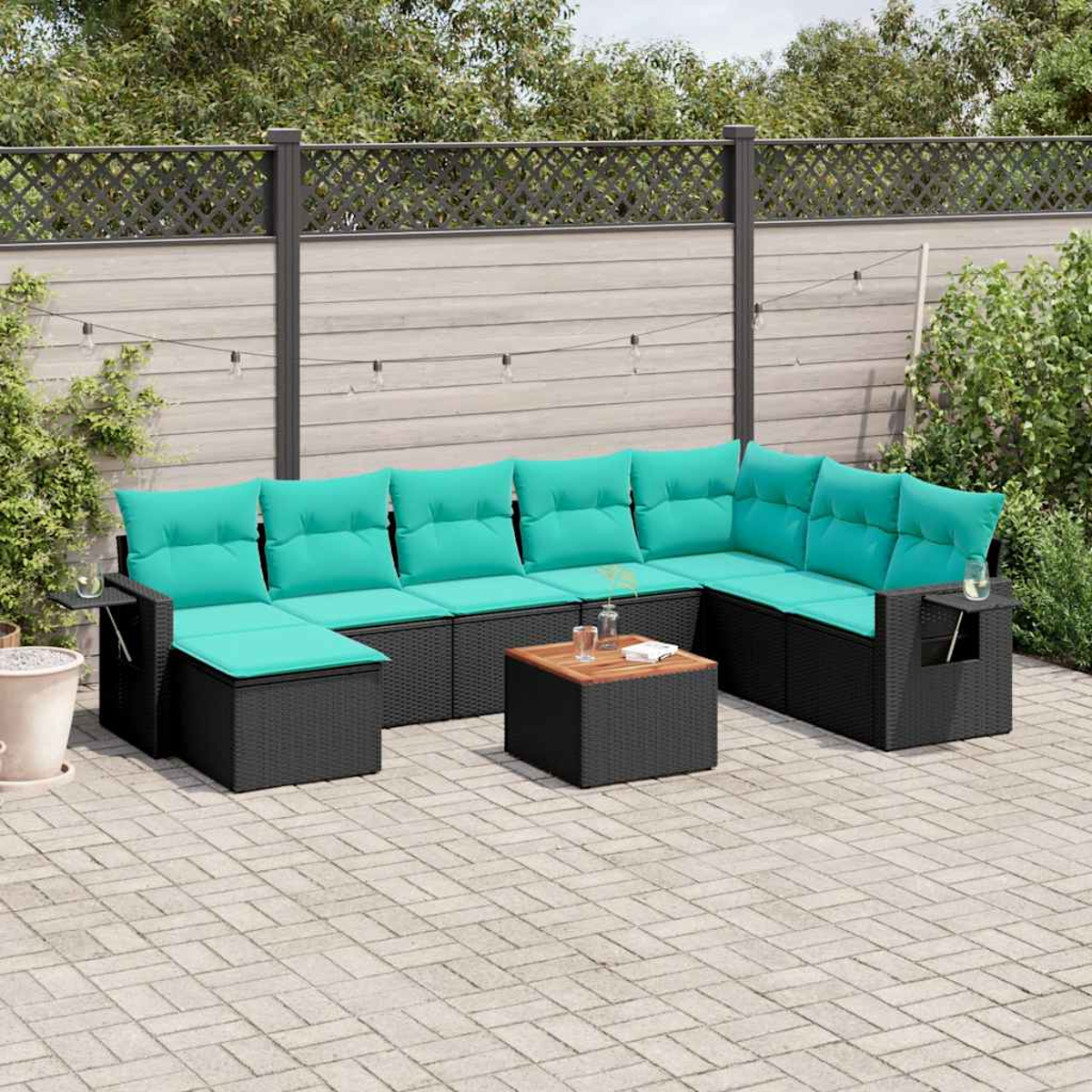 Ein Outdoor-Terrassen-Set mit schwarzem Korbgeflecht und türkisfarbenen Kissen steht auf einer Backstein-Terrasse mit einem Holztisch.