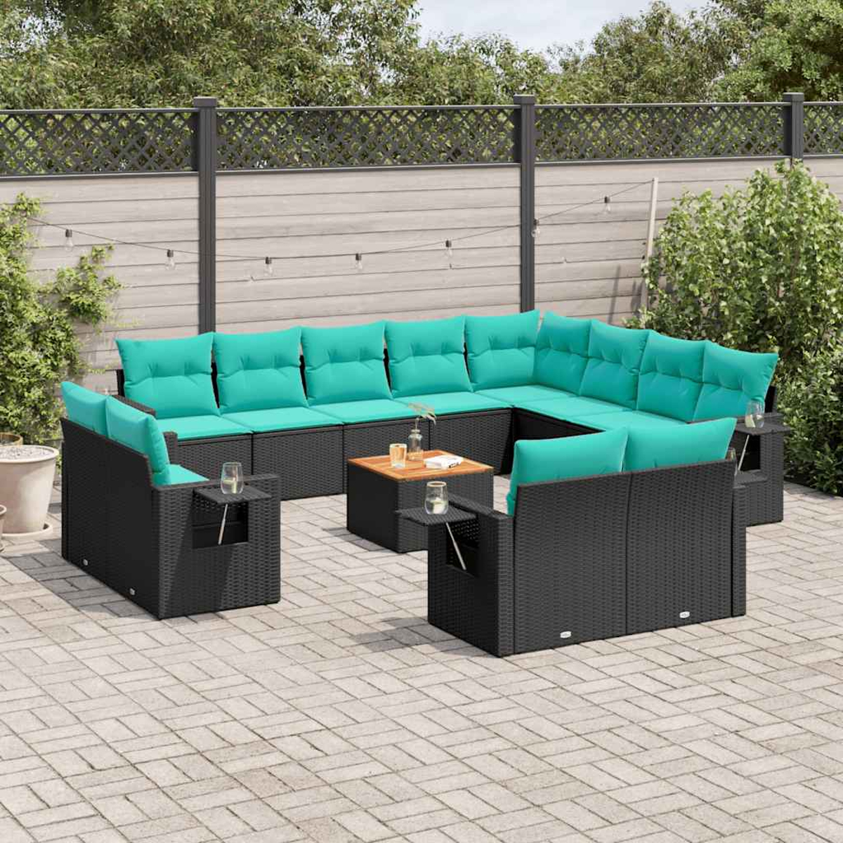 Un sofá seccional moderno al aire libre con cojines turquesa. Está colocado en un patio con mesas de madera. El fondo tiene una valla y plantas.