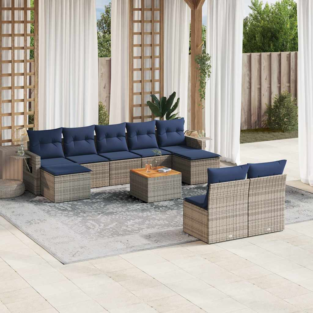 Outdoor-Terrassenset mit blauen Kissen und einem Holztisch. Die Szene umfasst weiße Vorhänge, einen gemusterten Teppich und Grün im Hintergrund.