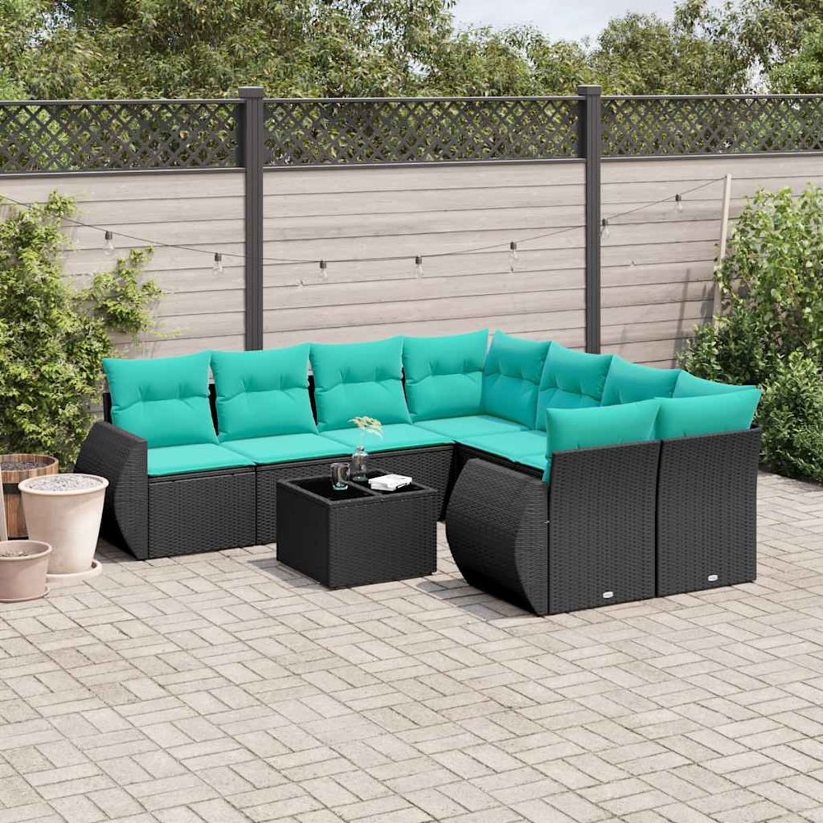 Outdoor-Ecksofa mit türkisfarbenen Kissen. Ein kleiner Tisch und Topfpflanzen stehen auf der Terrasse. Im Hintergrund befinden sich ein Zaun und Bäume.