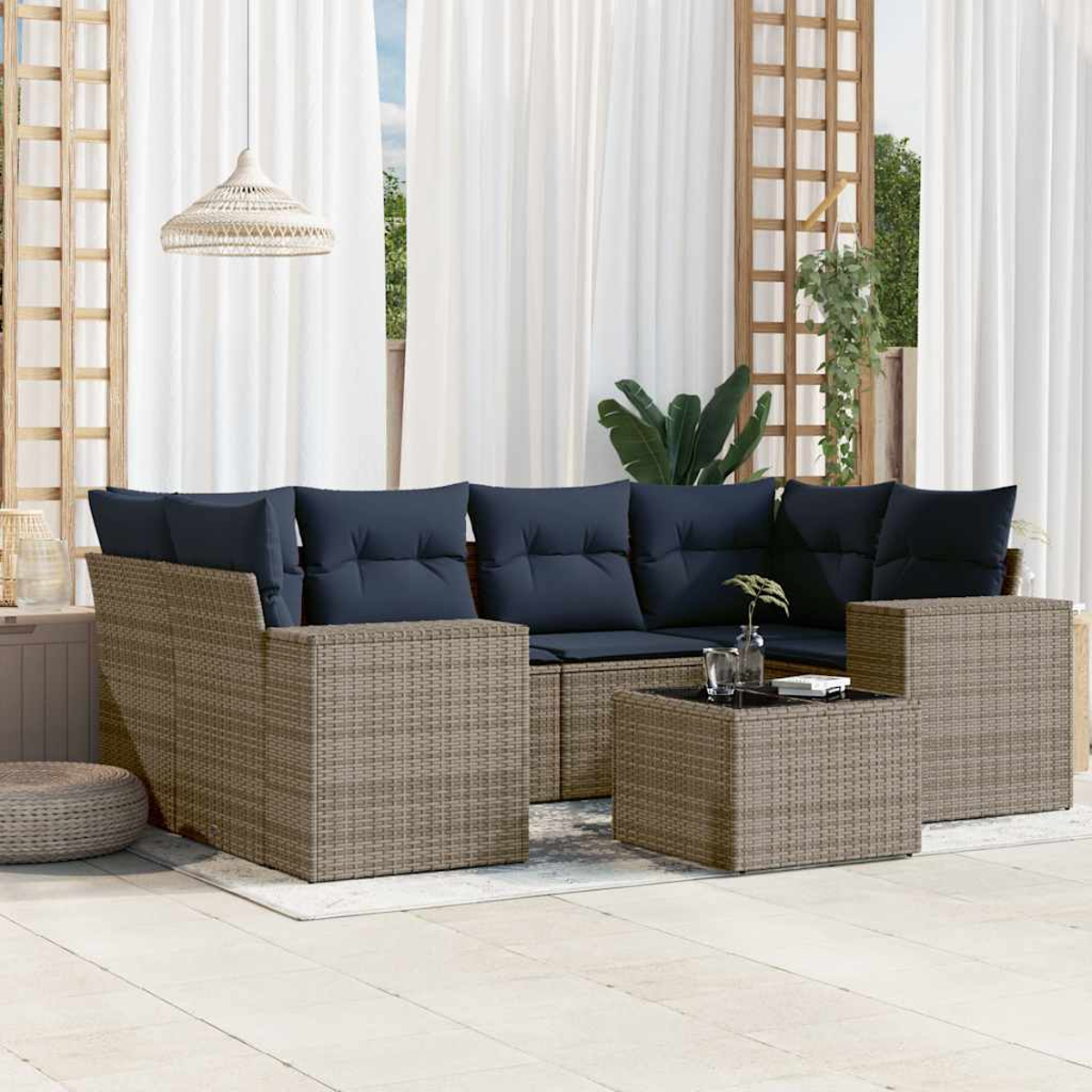 Garten-Sitzgruppe mit blauen Kissen auf einer Terrasse. Beinhaltet ein Sofa, einen Couchtisch und eine gewebte Lampe. Weiße Vorhänge im Hintergrund.