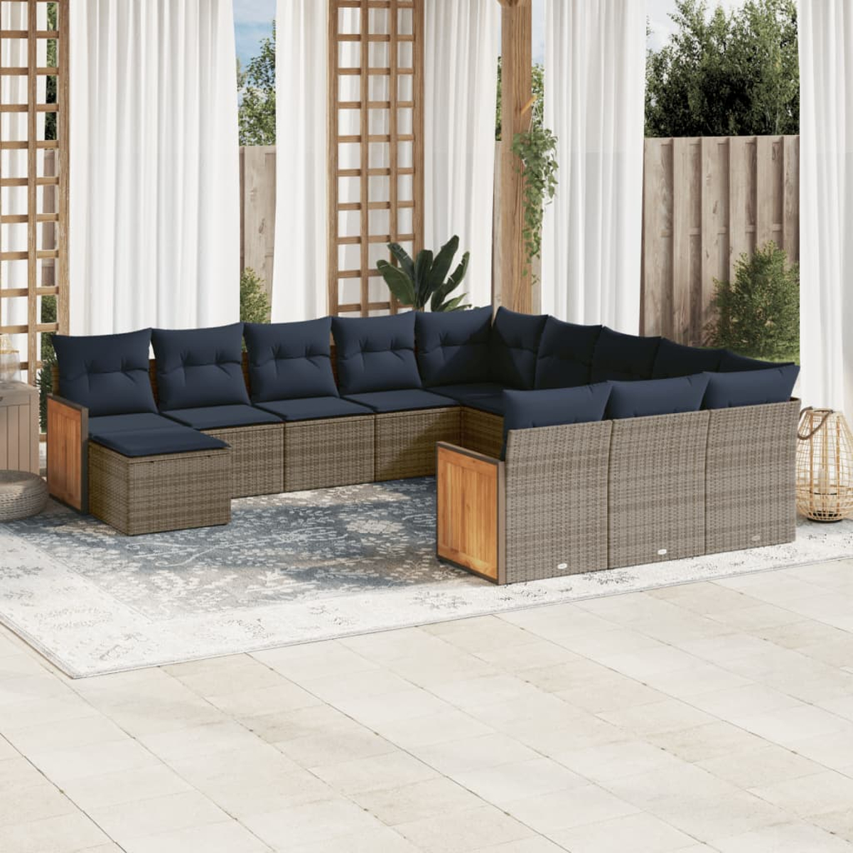 Outdoor-Ecksofa mit marineblauen Kissen auf einem grauen Teppich. Im Hintergrund weiße Vorhänge, Holzgitter und Grün.