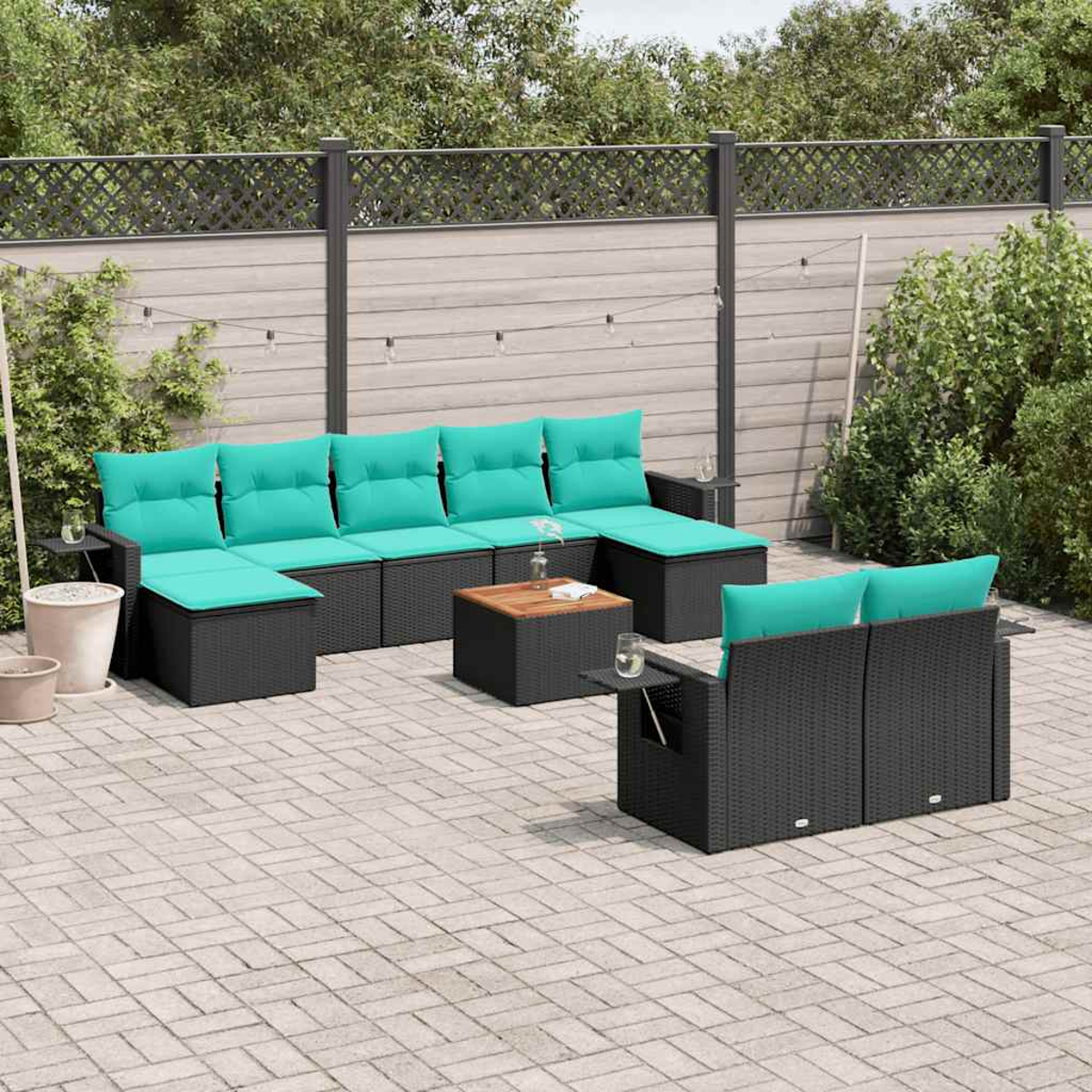 Terrassen-Set. Schwarze Korbmöbel mit türkisfarbenen Kissen. Enthält Sofa, Ottoman, Couchtisch und Beistelltische. Graue Pflastersteine.