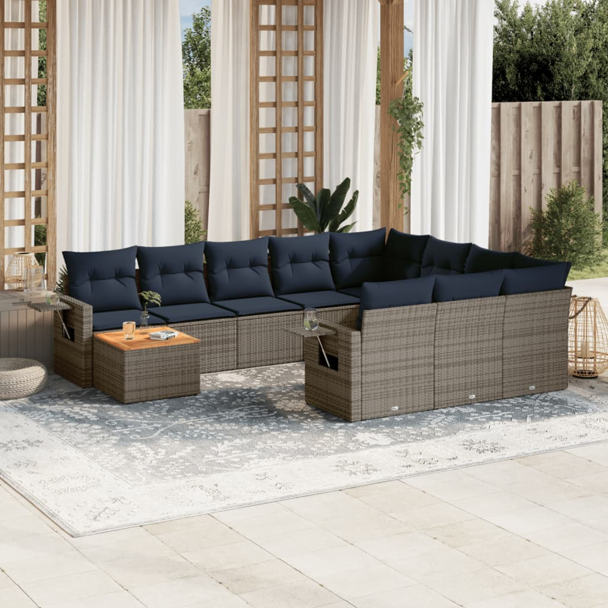 Outdoor-Ecksofa mit marineblauen Kissen. Davor ein Holztisch und ein Teppich. Weiße Vorhänge und Holzzaun im Hintergrund.