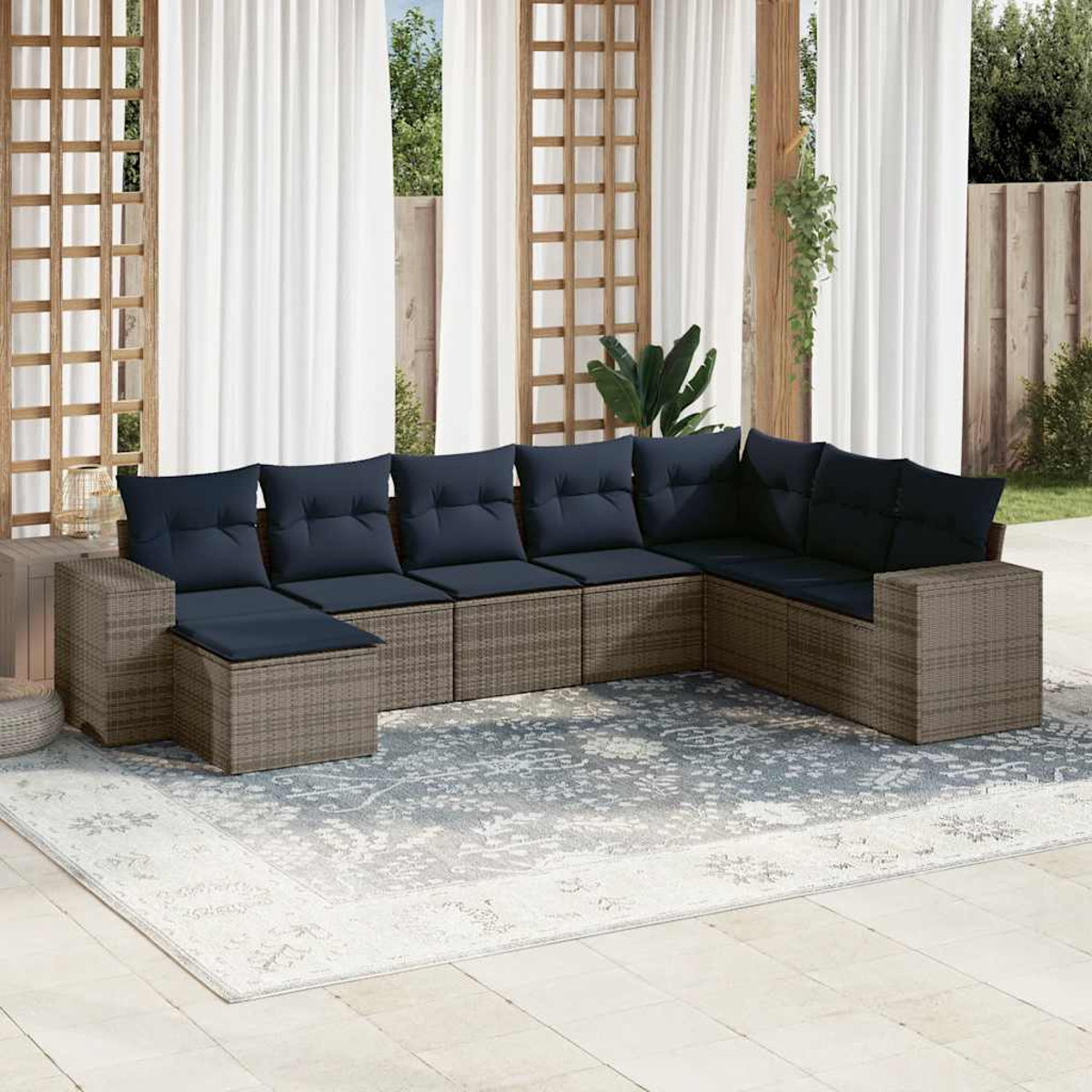 Outdoor-Ecksofa mit blauen Kissen auf einem gemusterten Teppich. Weiße Vorhänge und Holzgitter im Hintergrund.