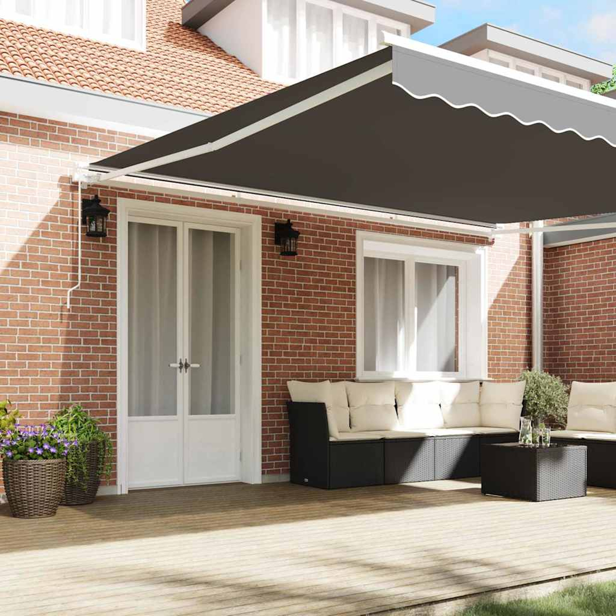 Eine Terrasse mit schwarzer Markise, Ziegelmauern und Holzterrasse. Es gibt eine Sitzecke mit schwarzen Möbeln und weißen Kissen.