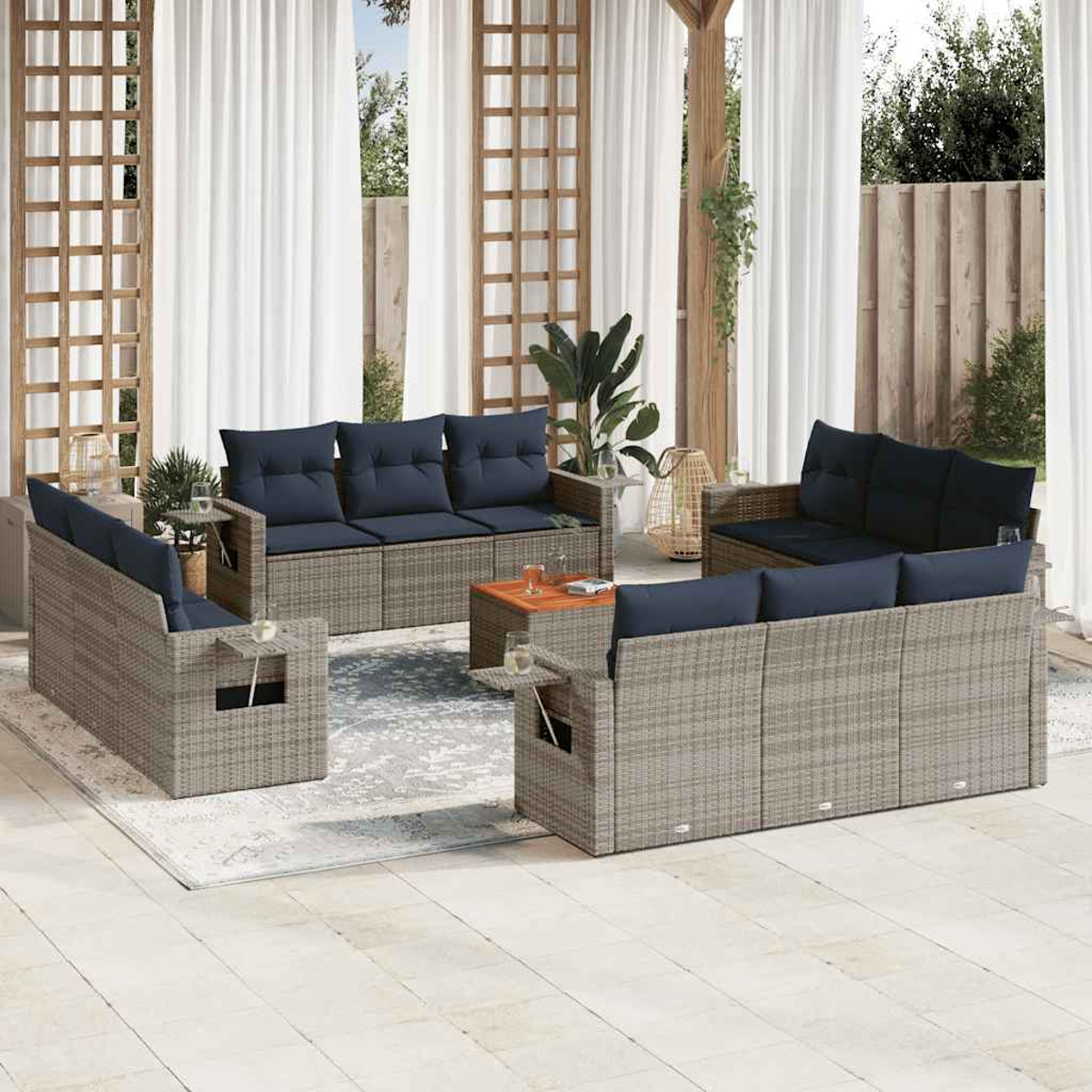 Gartenmöbel-Set: graue Korbsessel mit marineblauen Kissen, ein Holztisch und weiße Vorhänge im Freien.