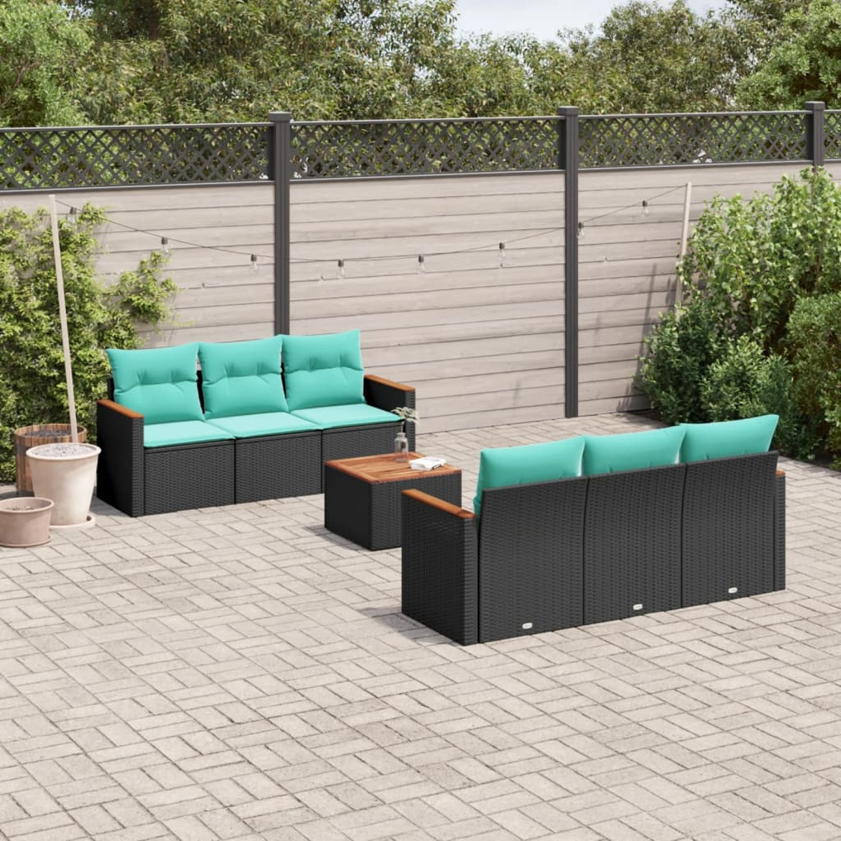 Garten-Set mit schwarzen Möbeln und tealfarbenen Kissen. Enthält Sofa, Stühle und Couchtisch auf einer Steinpflasterung.