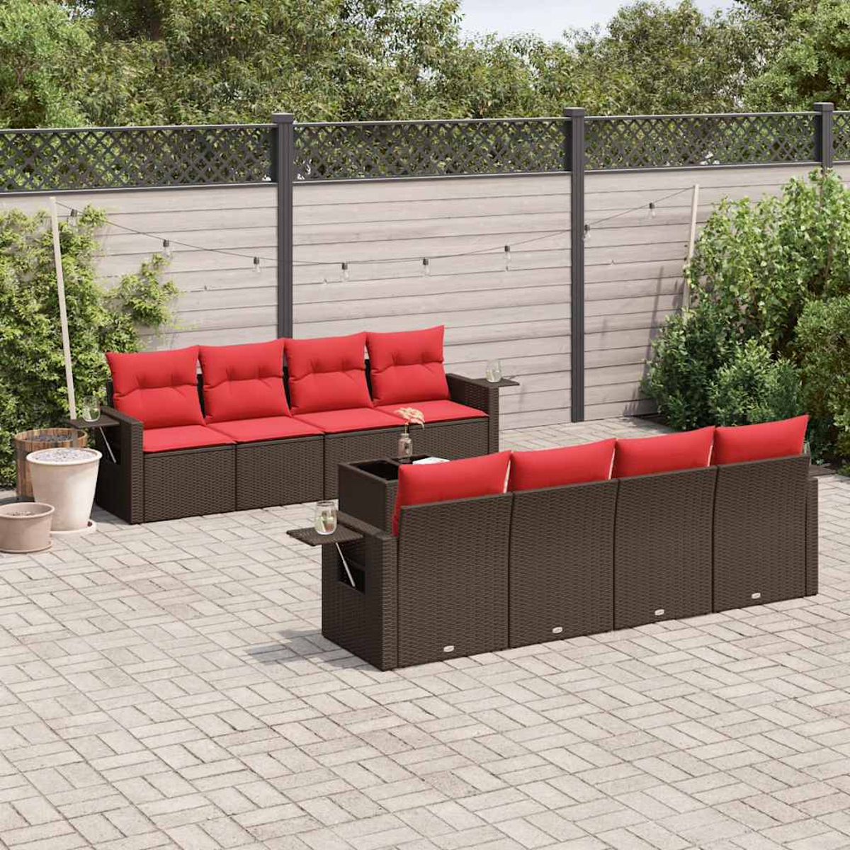 Terrasse im Freien mit zwei braunen Korbsesseln mit roten Kissen. Die Kulisse ist eine gepflasterte Terrasse mit einem Zaun und Grün im Hintergrund.