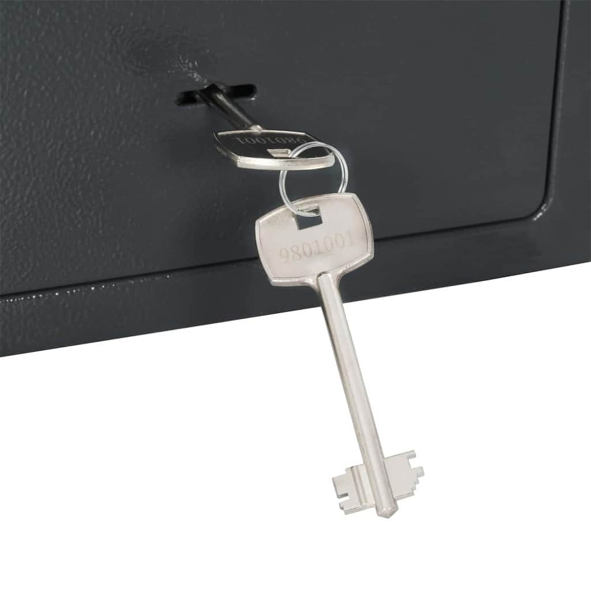 Primo piano di una cassaforte grigio scuro con chiavi inserite. Una chiave con '9801001' è attaccata a un anello con un'altra chiave.
