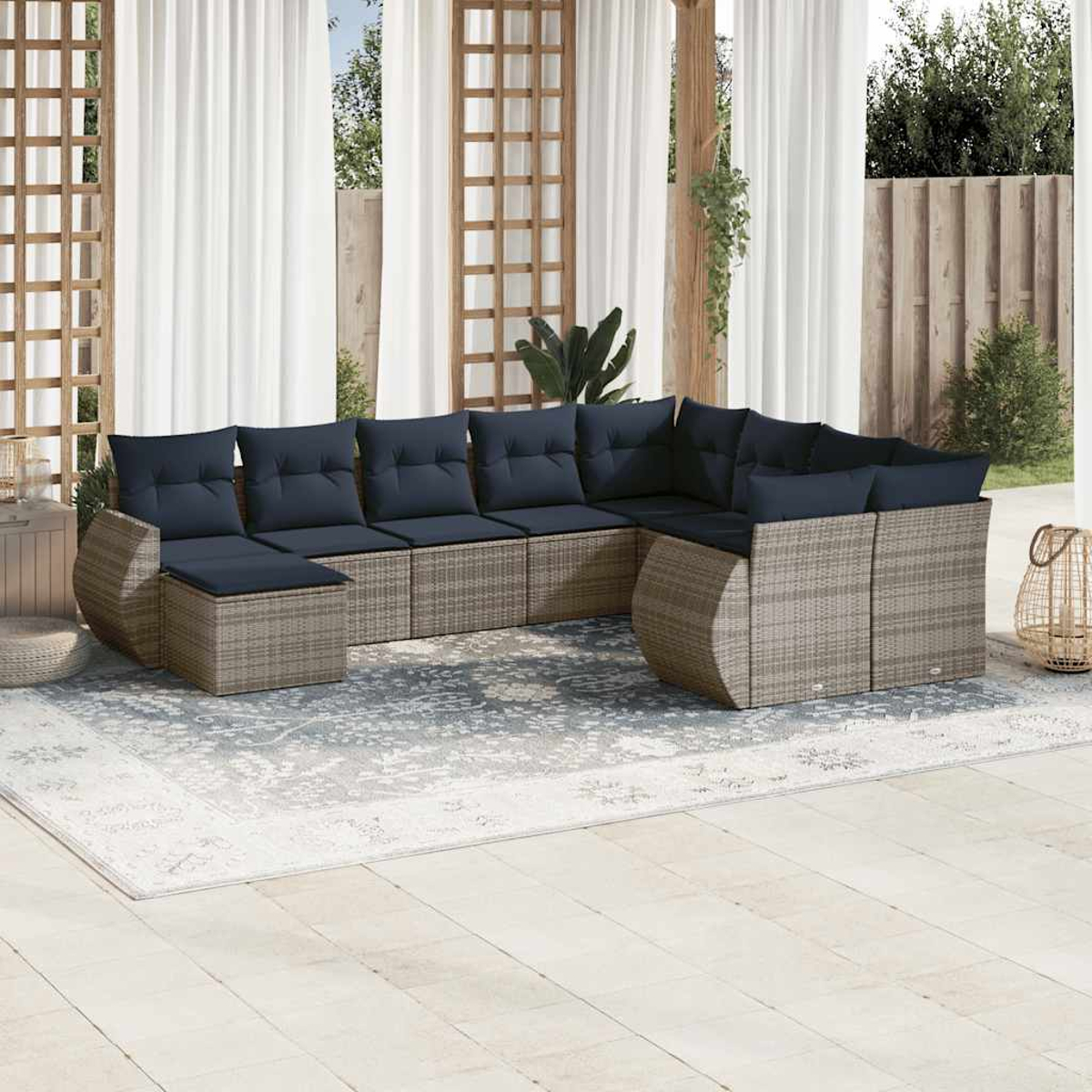 Outdoor-Ecksofa mit marineblauen Kissen auf einem gemusterten Teppich. Weiße Vorhänge und Holzkonstruktionen schaffen eine offene Terrasse.