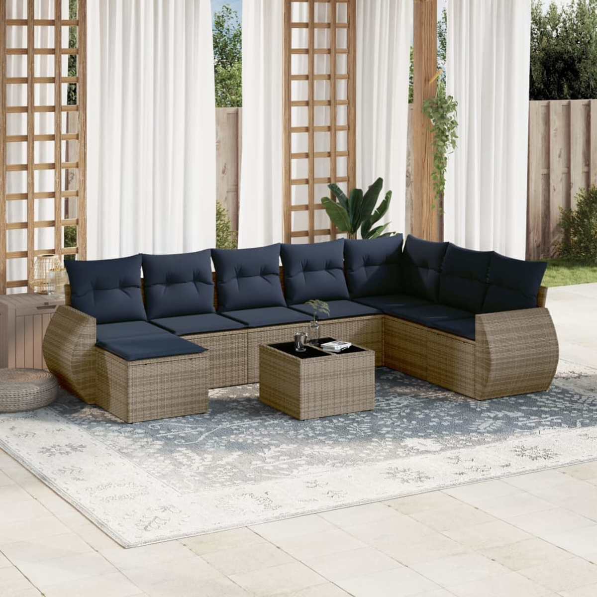 Outdoor-Sitzbereich mit großem Ecksofa, Couchtisch und gemustertem Teppich. Weiße Vorhänge und Holzrahmen im Hintergrund.