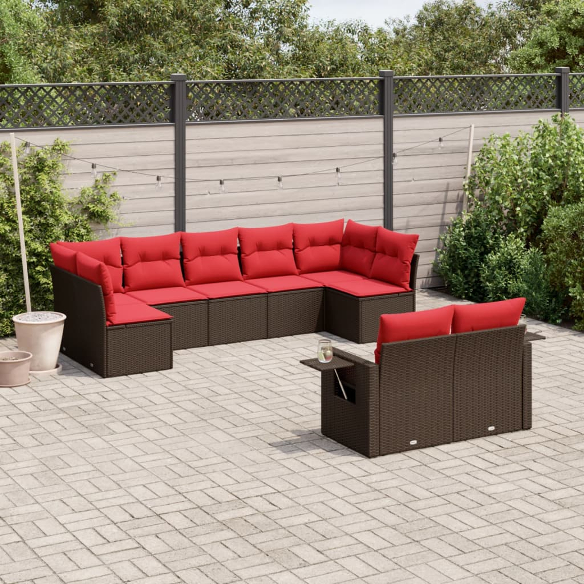 Gartenmöbel-Set. Braunes Korbmöbel mit roten Kissen. Ein kleiner Beistelltisch und ein zweites Sofa sind ebenfalls sichtbar. Ziegelboden.