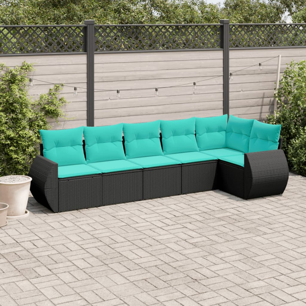 Ein Ecksofa mit türkisfarbenen Kissen im Freien steht auf einer Terrasse. Im Hintergrund befinden sich ein Zaun und Grün.