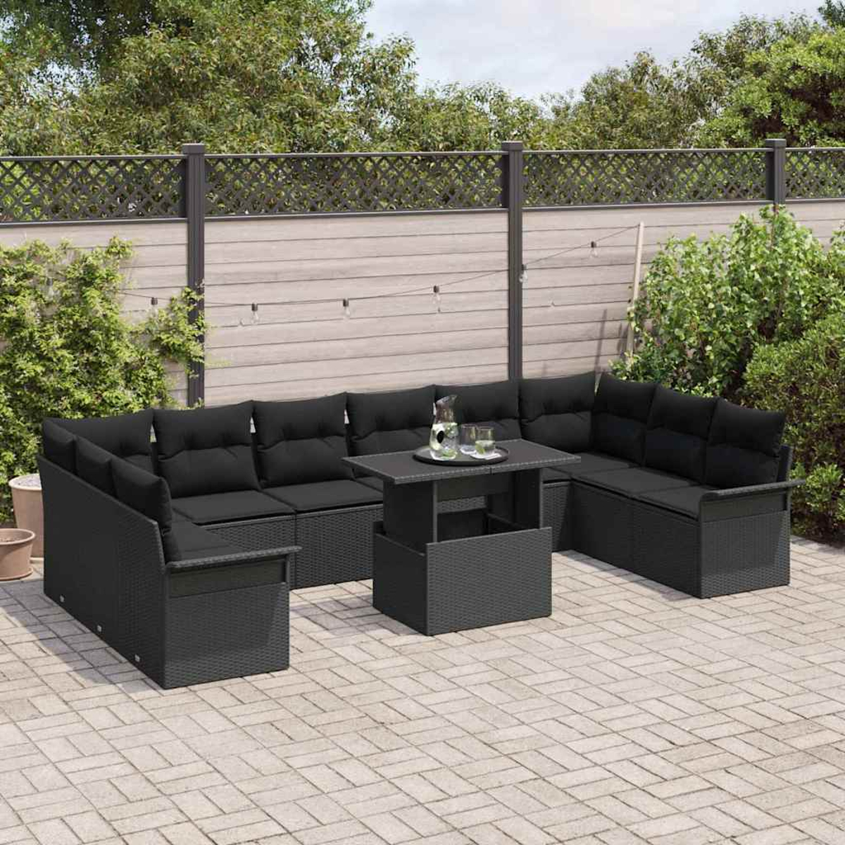 Schwarzes Rattan-Sofa mit Kissen und Tisch im Freien auf einer Ziegelterrasse. Grünes Laub und Zaun im Hintergrund.