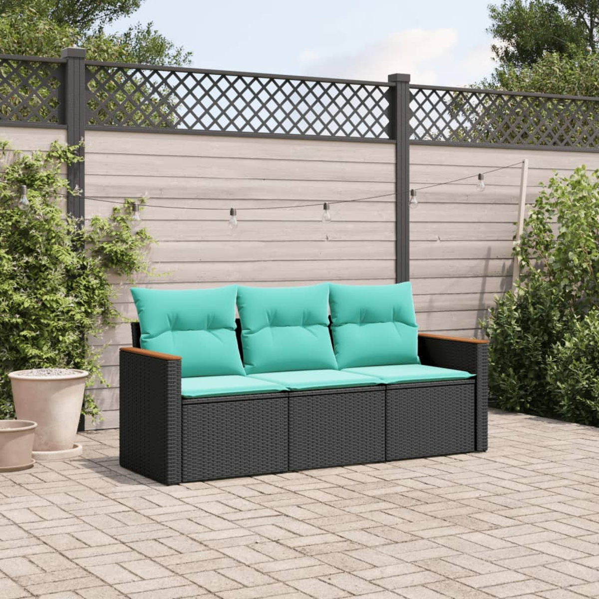 Gartensofa mit türkisfarbenen Kissen, schwarzem Korbgeweberahmen, Holzarmlehnen und Holzzaun im Hintergrund.