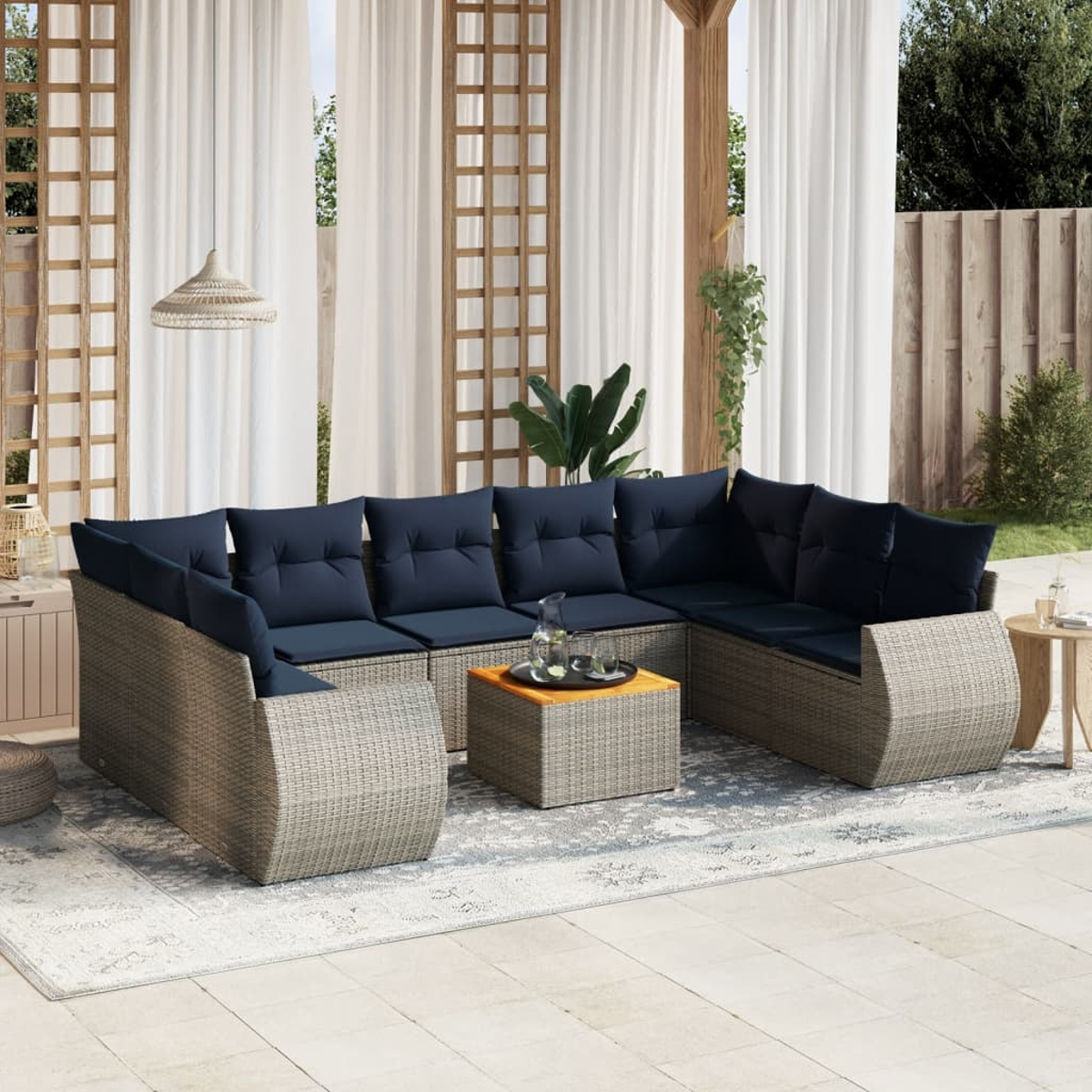 Outdoor-Ecksofa mit marineblauen Kissen, auf einem gemusterten Teppich. Ein kleiner Tisch hält Getränke. Weiße Vorhänge und Holzbalken sind im Hintergrund.