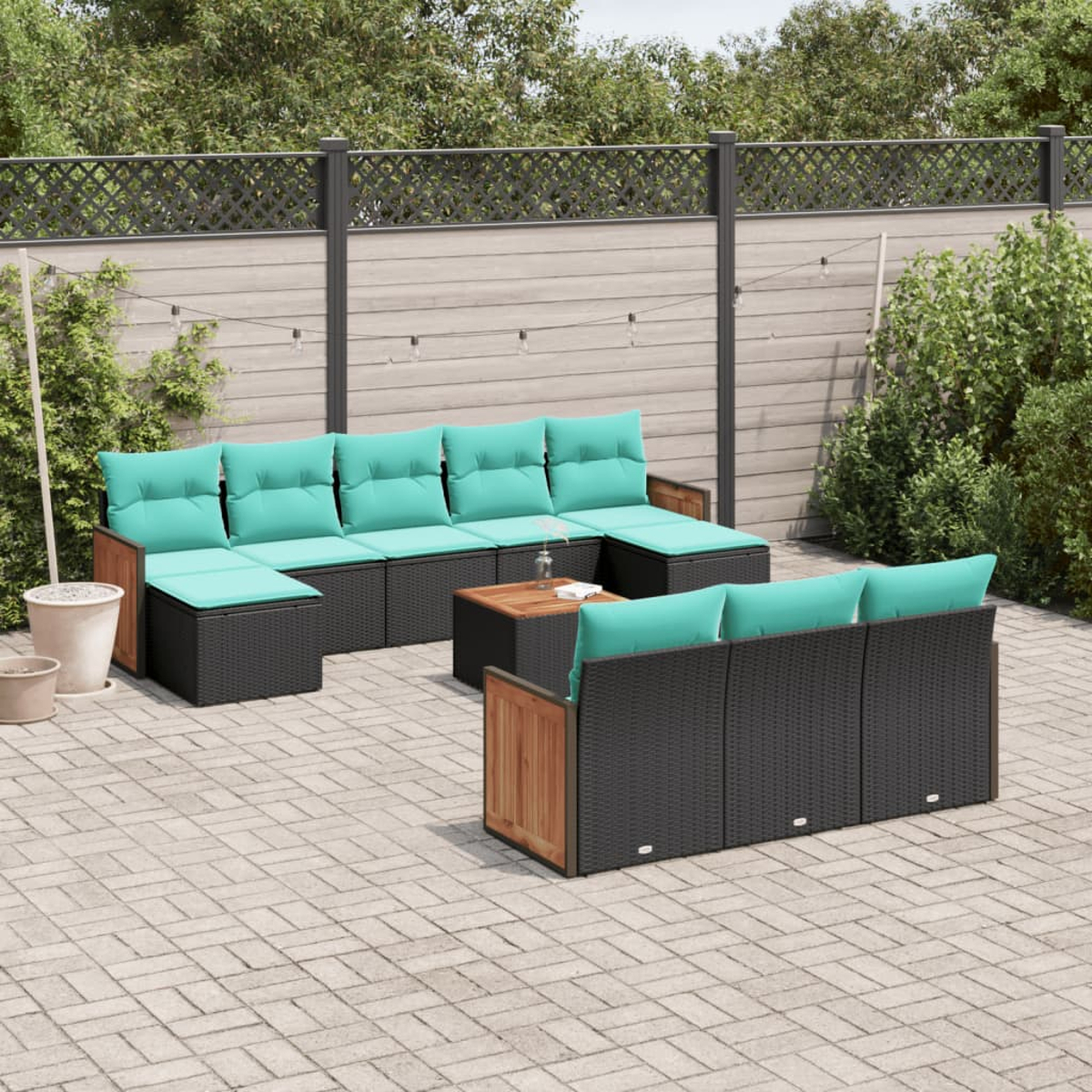 Outdoor-Ecksofa mit türkisfarbenen Kissen. Ein kleiner Holztisch. Terrasse mit Steinpflaster und Holzzaun im Hintergrund.