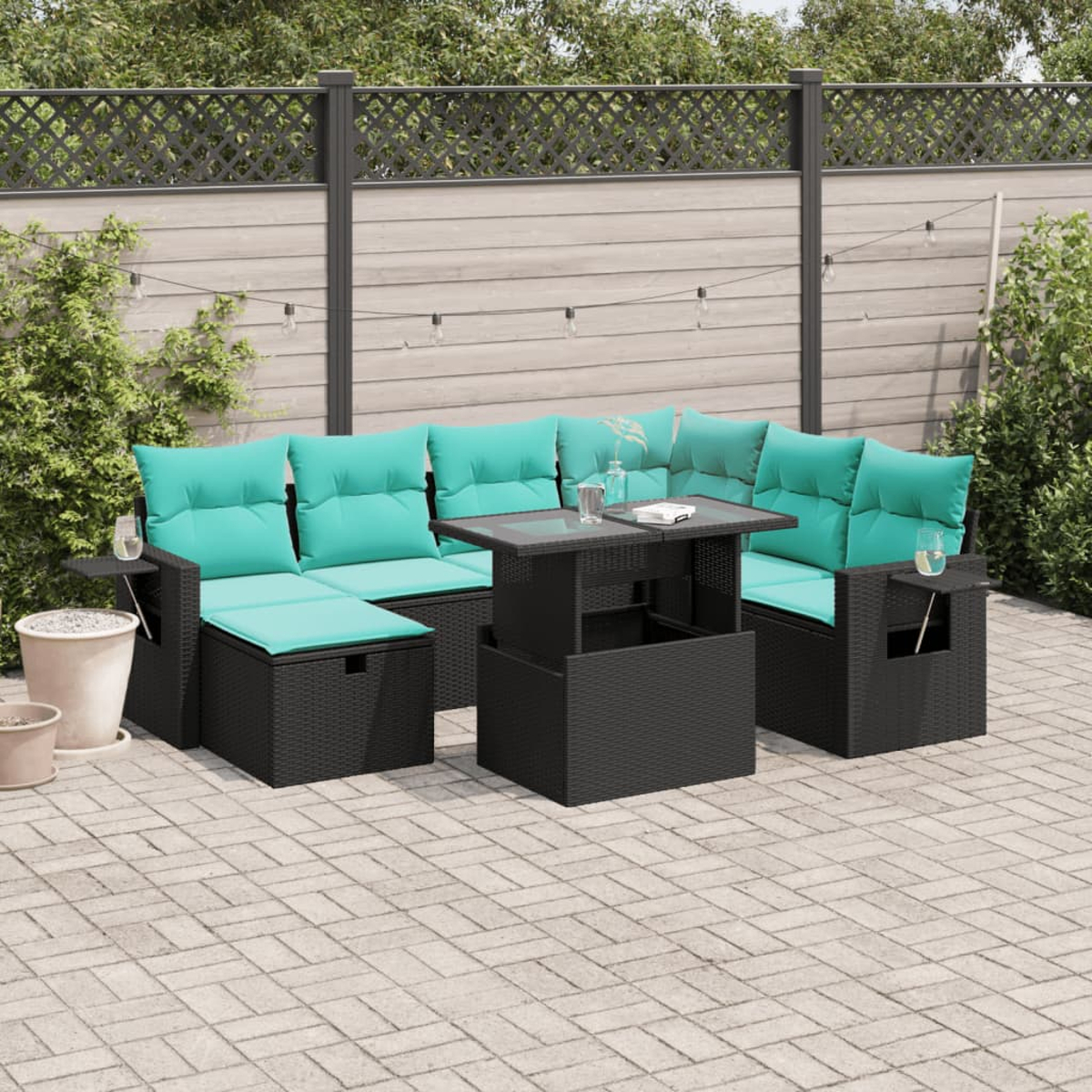 Terrassenmöbel mit schwarzem Korbmöbeln, tealfarbenen Kissen, Glastischplatte und Holzzaun im Hintergrund.